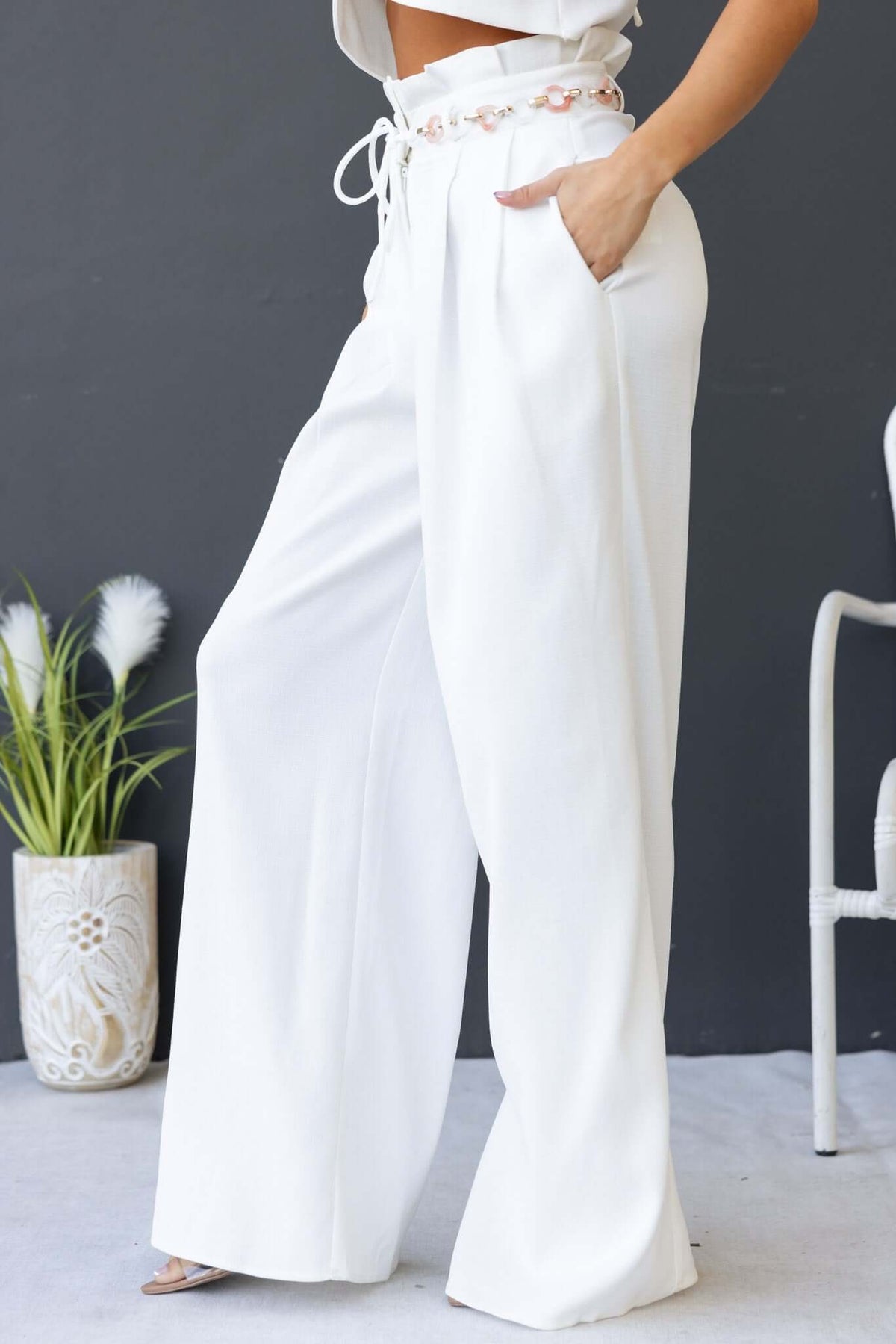 White paperbag waist pants with removable belt and pockets, featured in a stylish outfit.