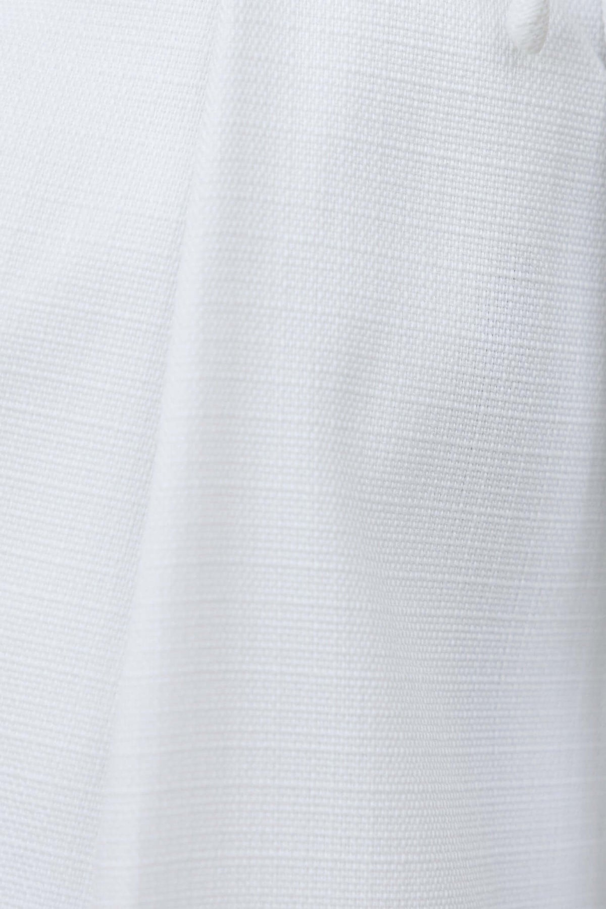 Close-up of textured white fabric featuring a linen look, highlighting the soft and elegant design of the Paytas Top.