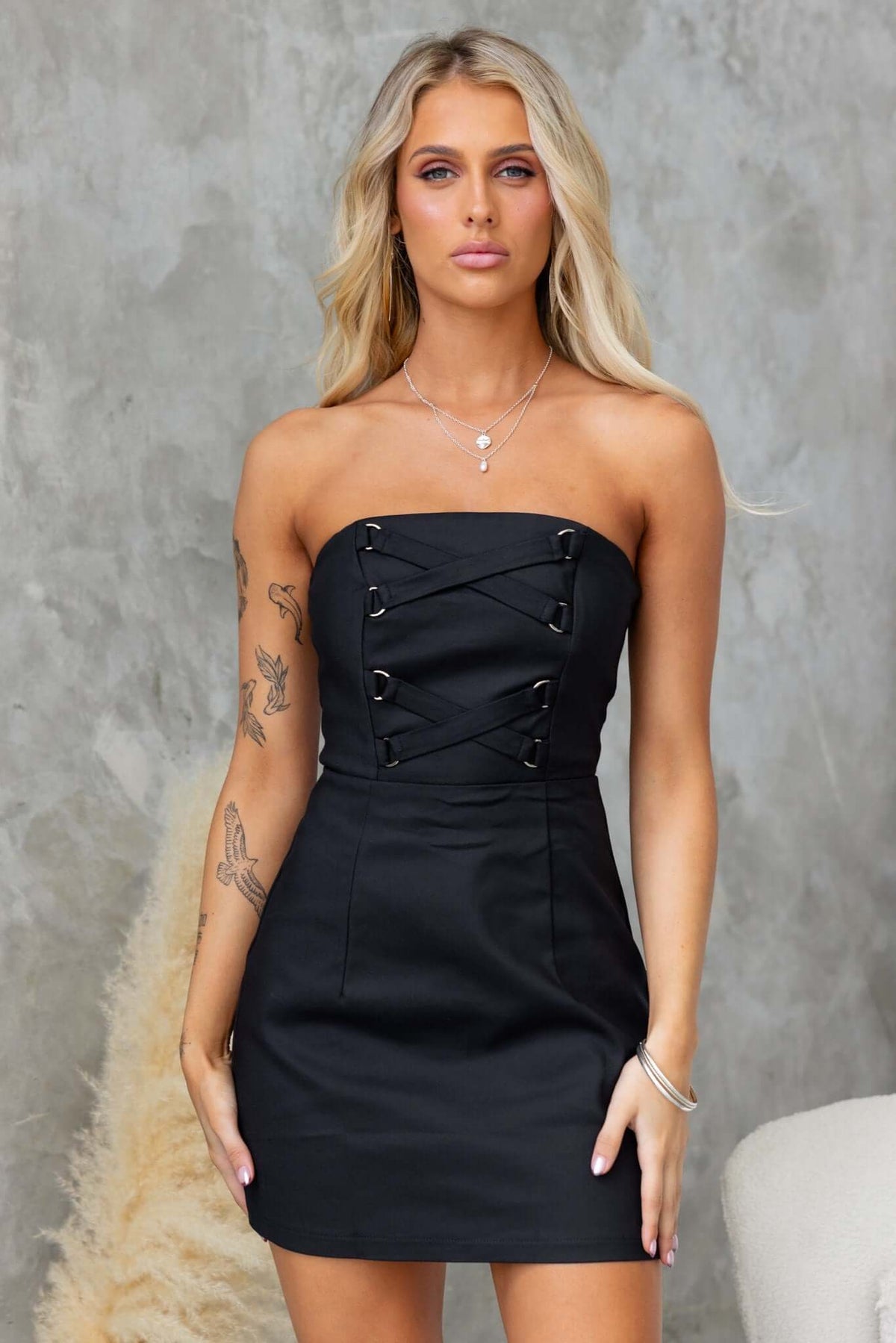 Strapless black Odelle dress featuring boning at bust and zip closure, styled by model with long blonde hair.
