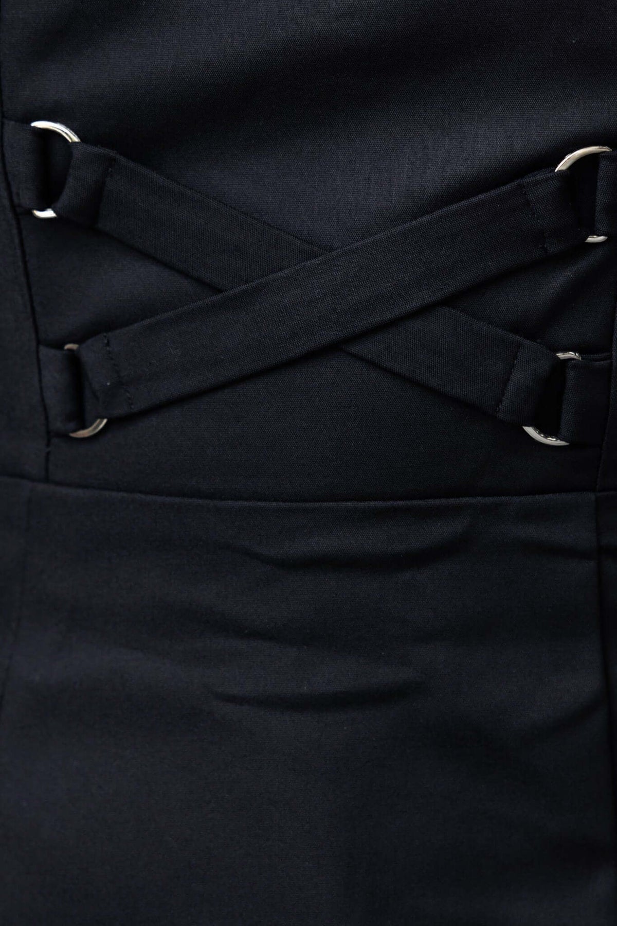 Close-up of black Odelle dress featuring cross straps and silver hardware detailing.