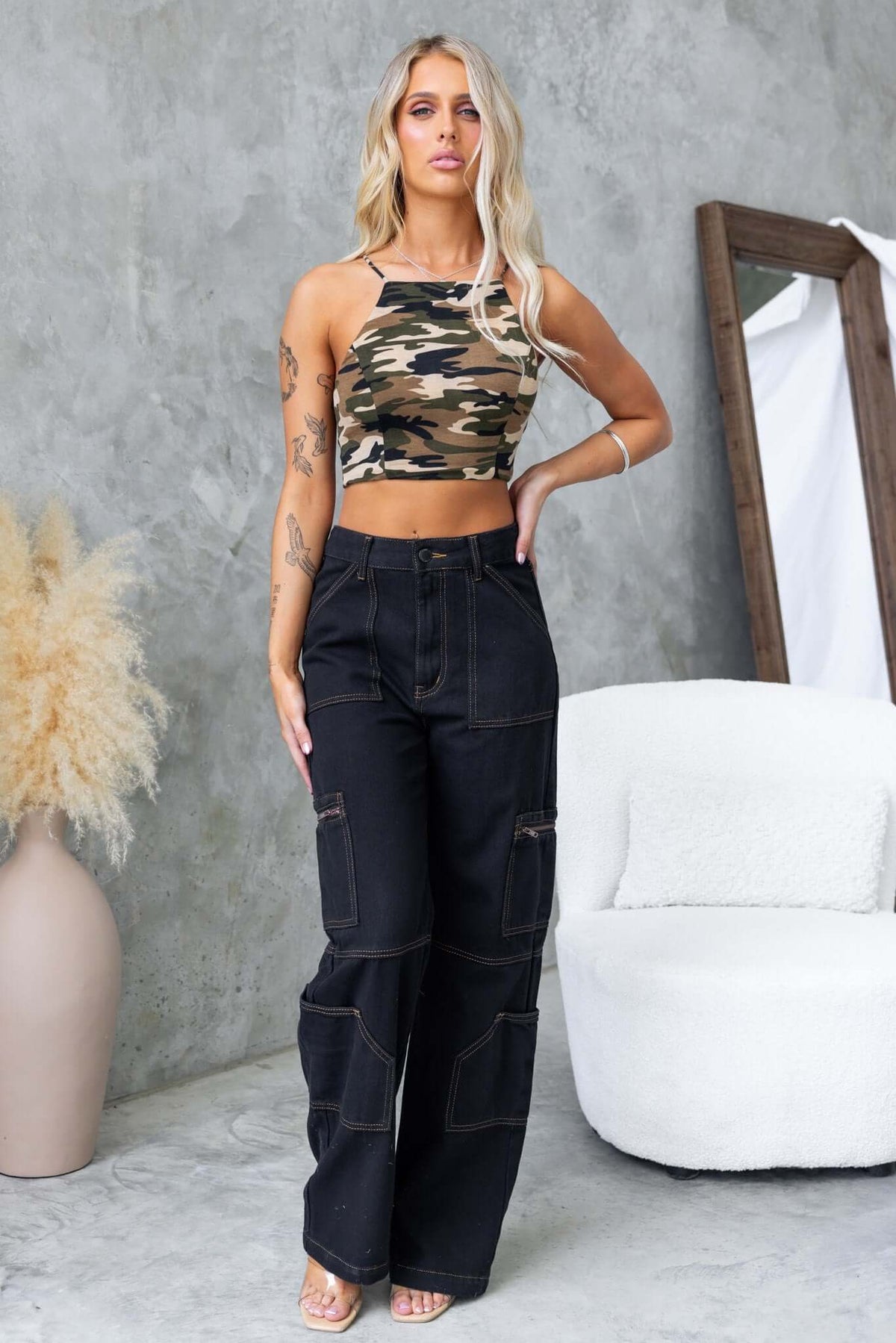 Stylish woman in a camo halter top with black cargo pants, showcasing a modern streetwear look.