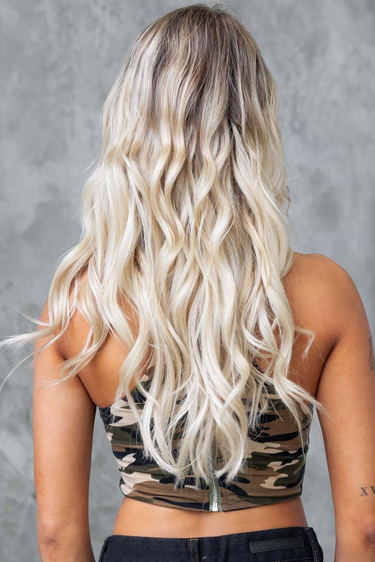 Back view of a woman wearing a Camouflage Halter Top with wavy blonde hair, showcasing a stylish zipper detail.