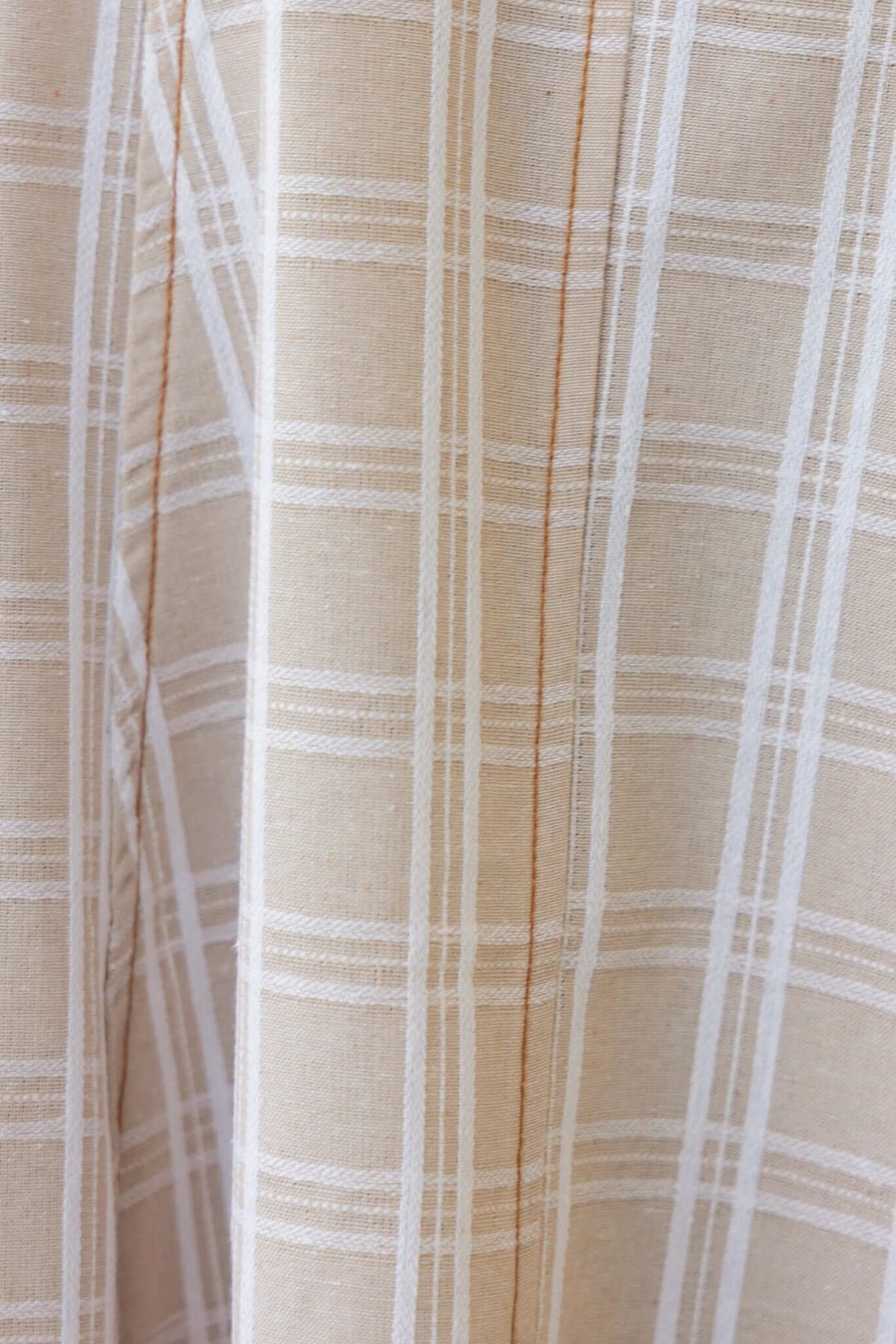 Detail of Harloh Midi Dress fabric featuring a beige and white checkered pattern with a linen texture.