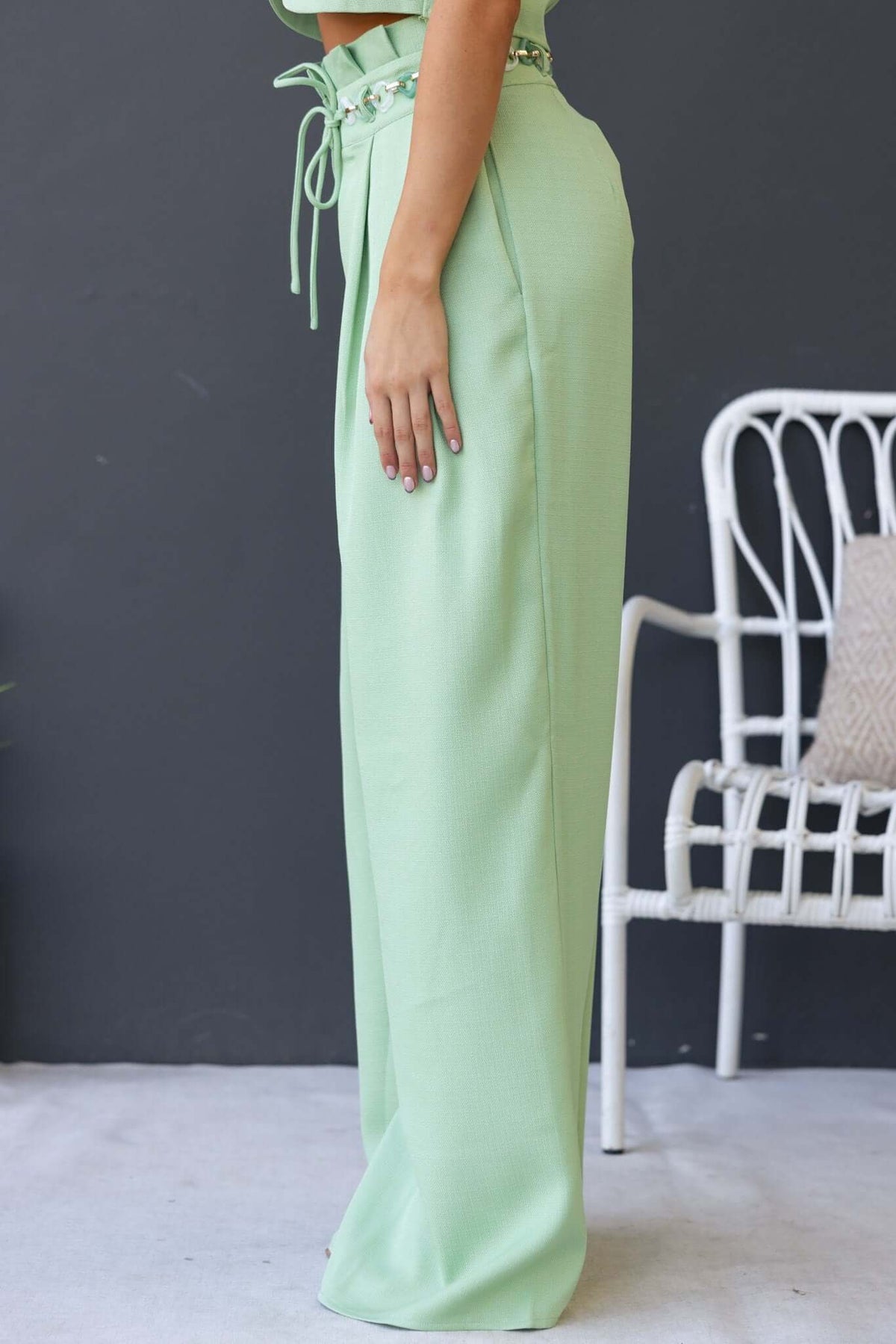 Side view of Paytas Pants featuring a paperbag waist, removable belt, and mint green fabric.