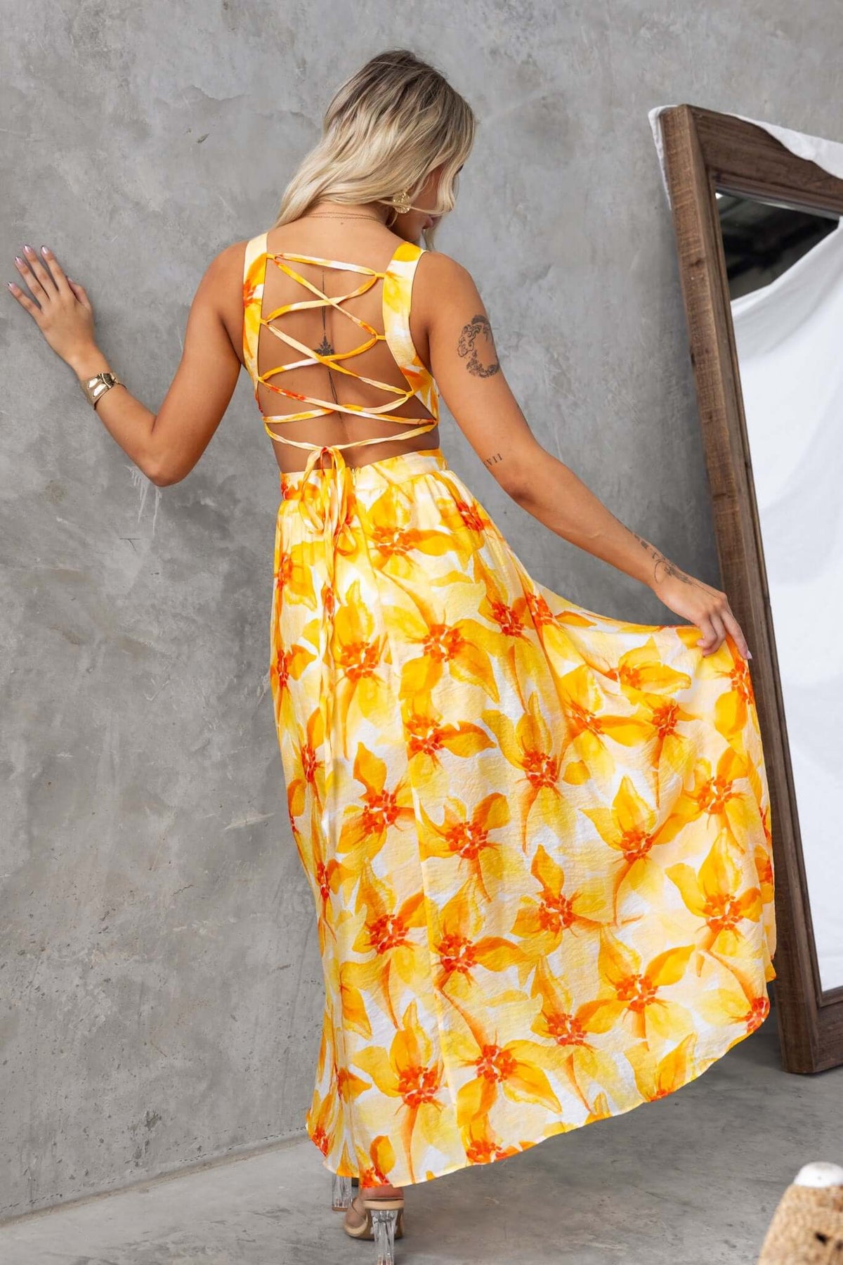 Model wearing Blancia Maxi Dress with floral print, featuring a crisscross back and flowy skirt.