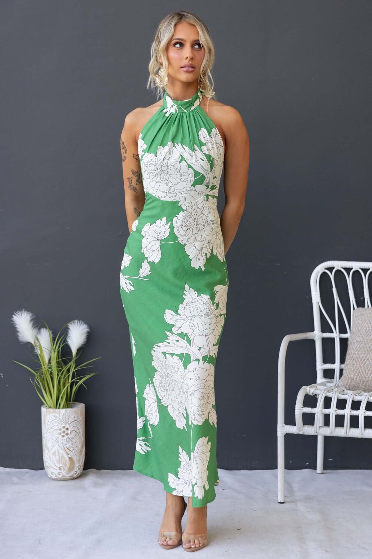 Model wearing the Forbidden Love Maxi Dress in green with white floral design, showcasing high tie neckline and fitted silhouette.