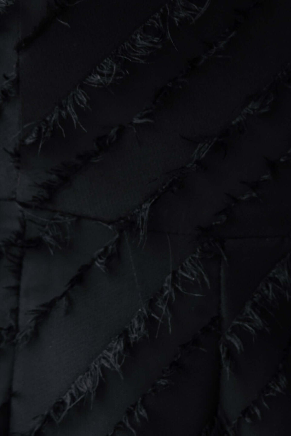 Close-up of black textured fabric with frayed detailing, showcasing the unique design elements of the Bossier Playsuit.