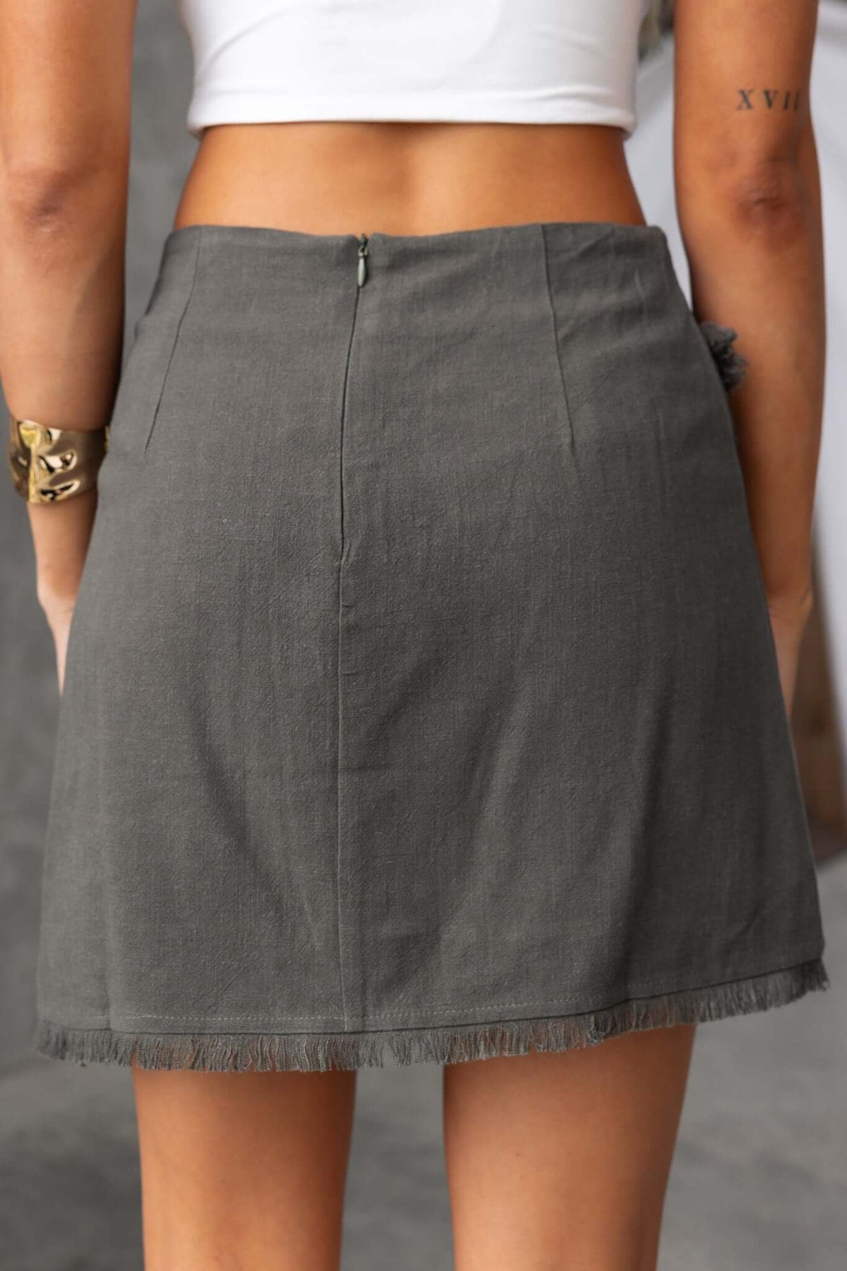 Back view of Invo Skirt in olive green with fringe hem, mid-high waist, and invisible zip closure.