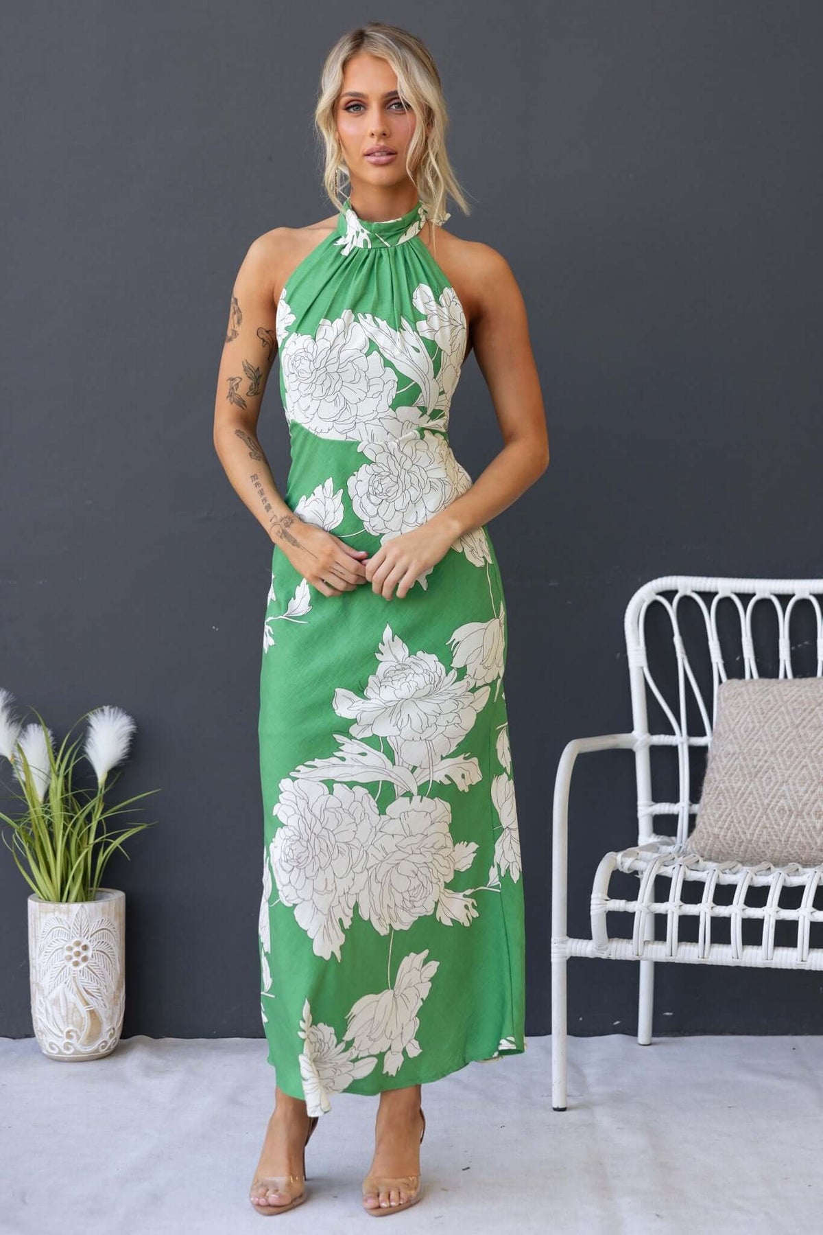 Model wearing a green floral Forbidden Love Maxi Dress with high tie neckline and back zipper, styled for summer.