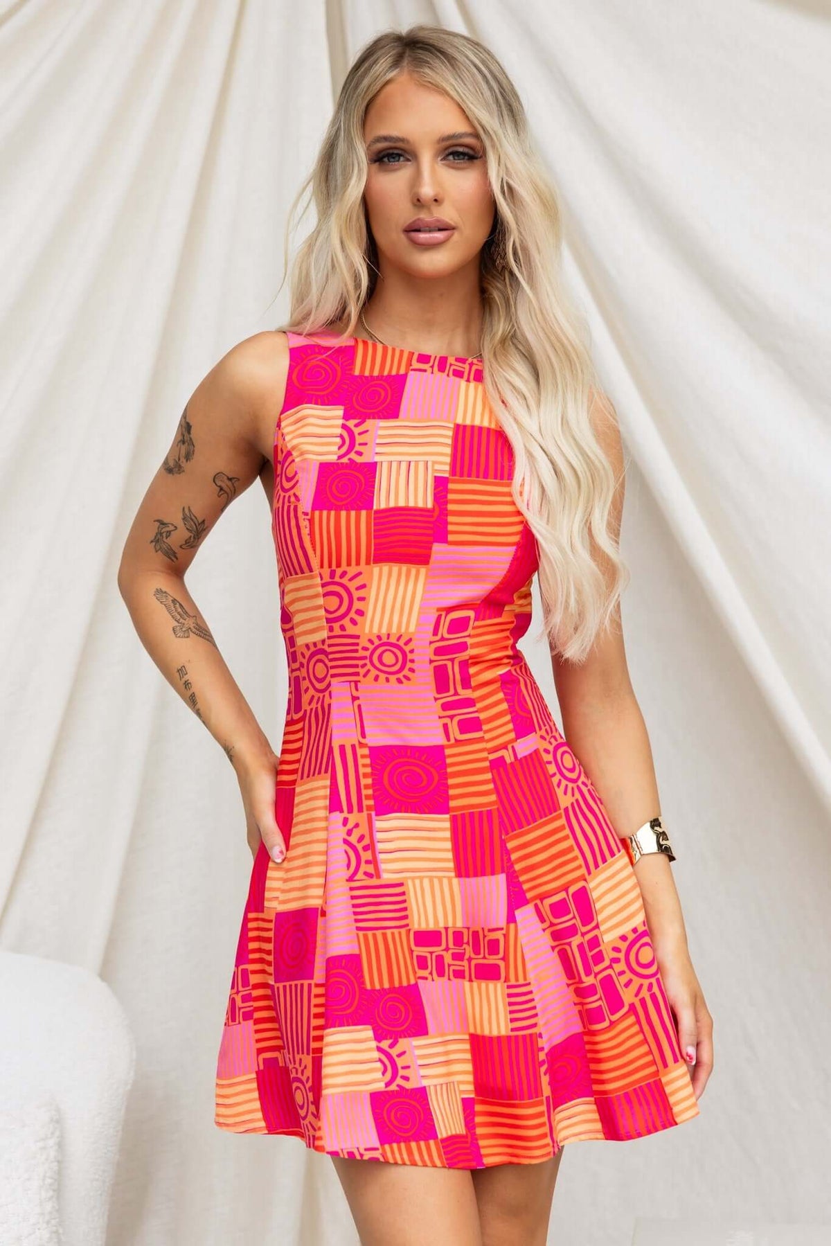 Goldrush Dress with vibrant pink and orange geometric pattern, featuring a high neckline and flared skirt.