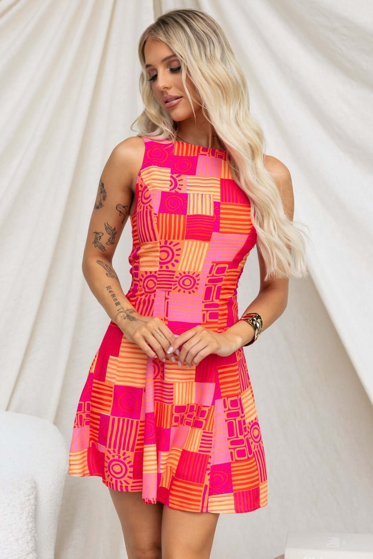 Woman wearing a vibrant pink and orange patterned Goldrush Dress with a high neckline and a flared skirt.
