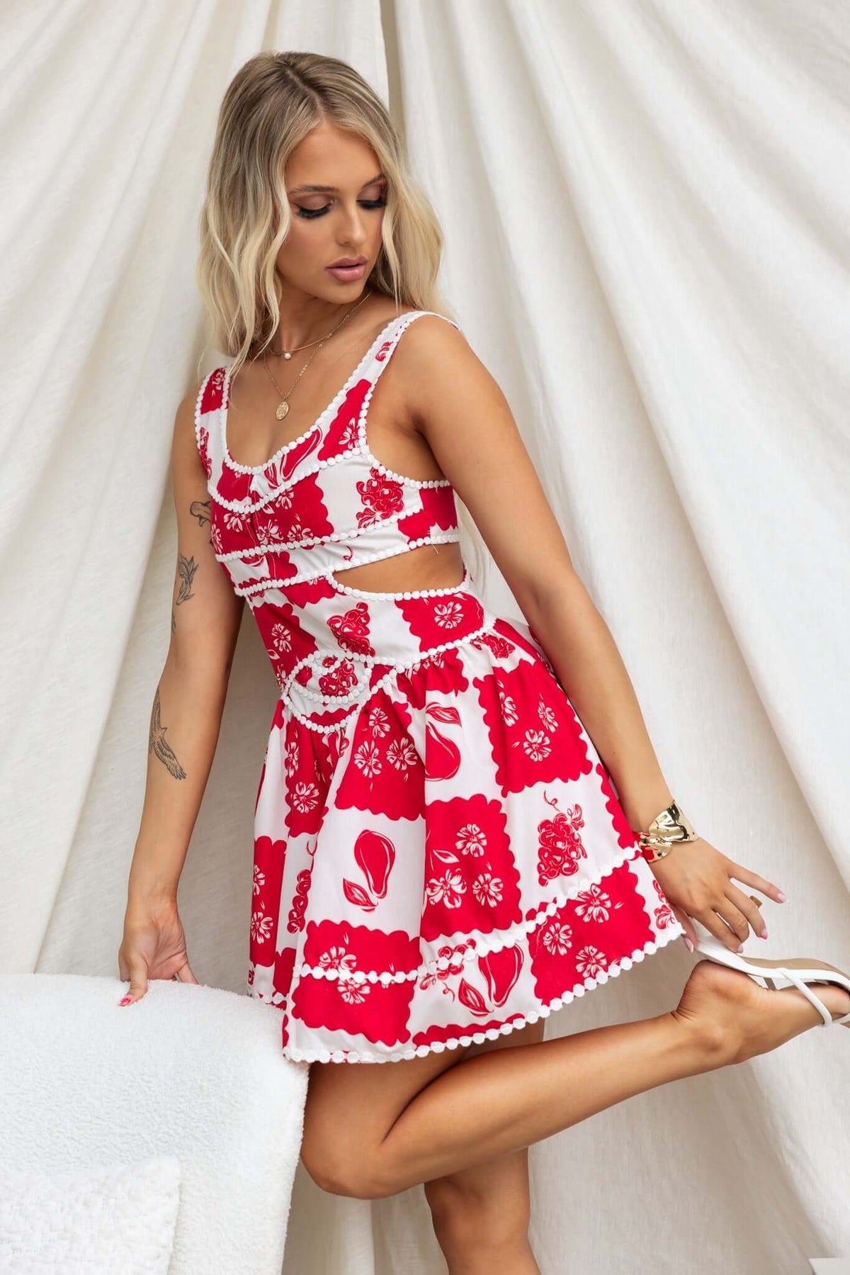 Model showcasing the Inara Dress, featuring adjustable straps and a cut-out waist in a red floral print.