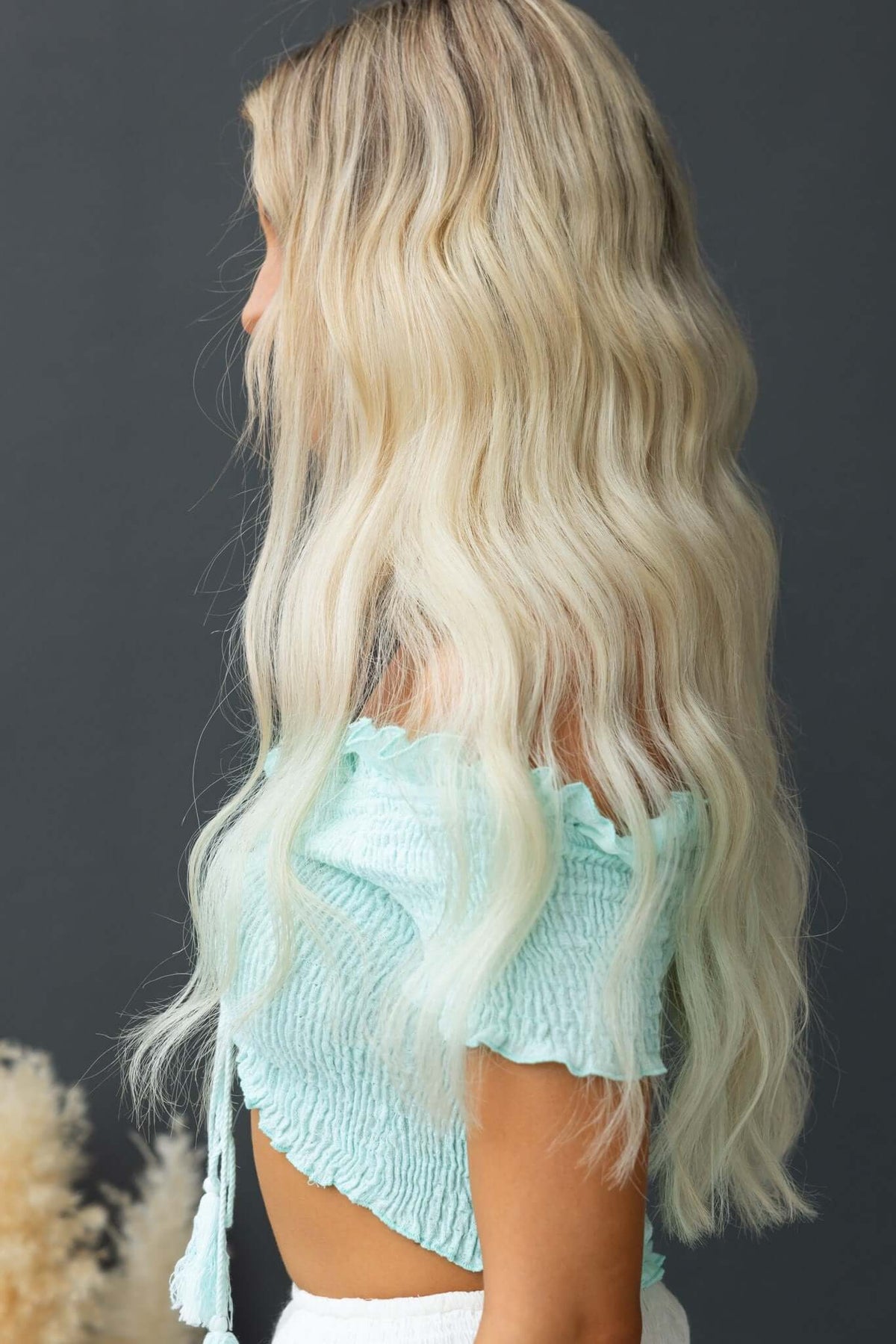 Model showcasing the Vitora Top, featuring a tie at the bust and a relaxed fit, styled with long wavy hair.
