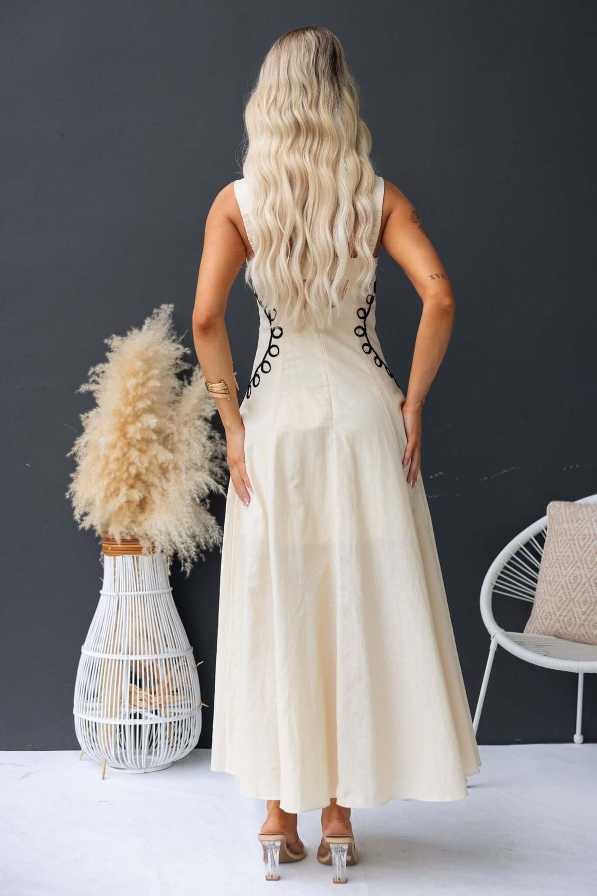 Back view of Huckle Maxi Dress featuring elastic and button details, styled with a natural backdrop.