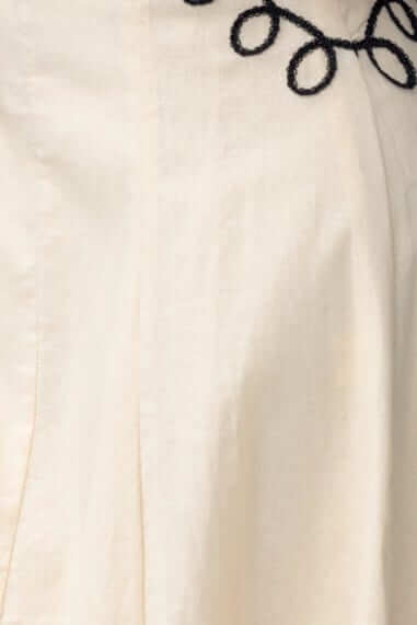 Close-up of the Huckle Maxi Dress showing the cream fabric and intricate black embroidery detail.