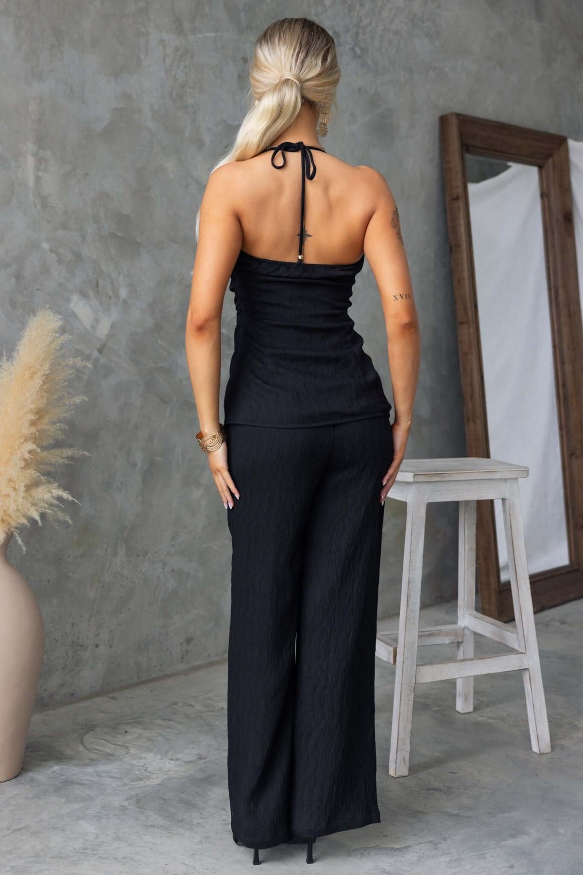 Kayce Set featuring a back view of a woman in a tie-neck halter top and non-stretch mid-high waist pants.