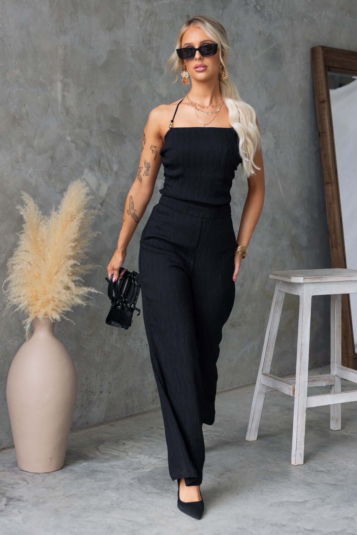 Model showcasing the Kayce set, a stylish black two-piece outfit with a tie neckline and mid-high waist pants.