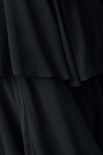 Close-up of the flowing fabric of a black maxi dress featuring layered ruffles and a V-neckline.