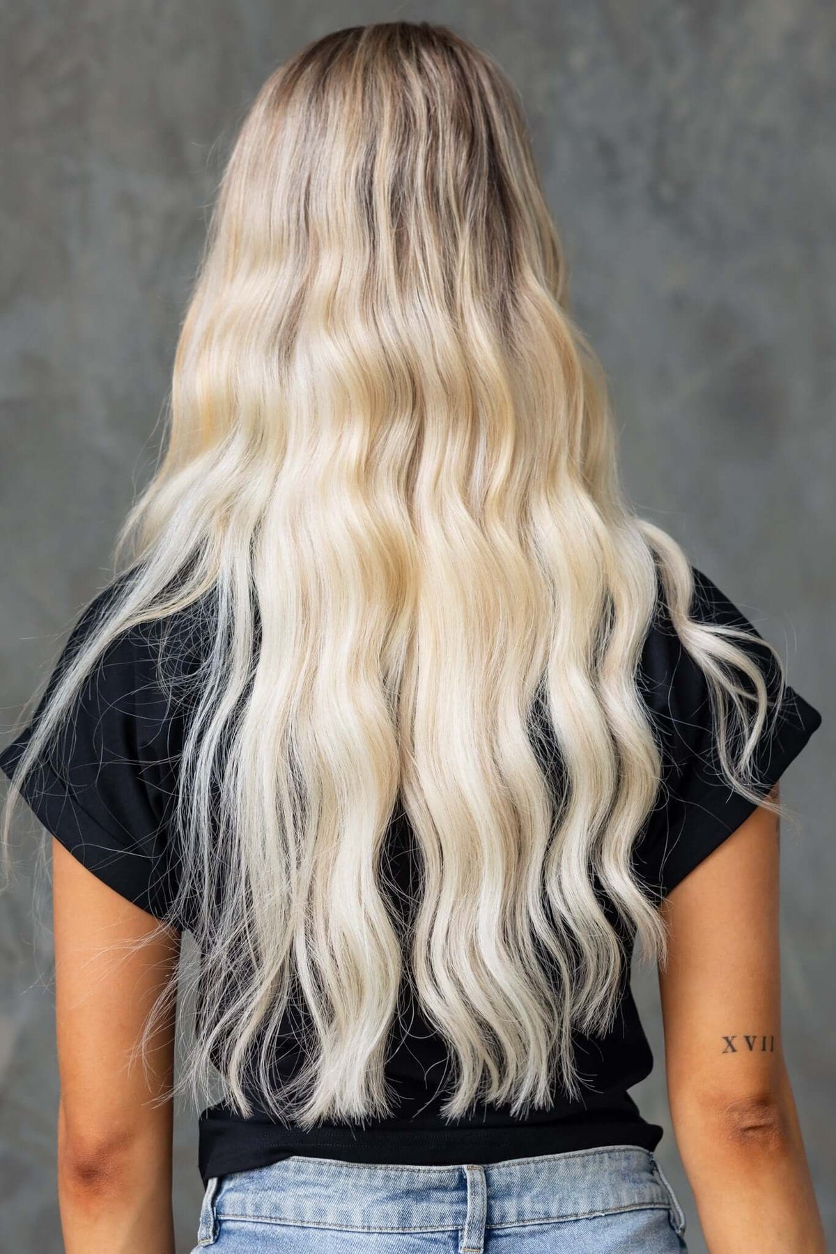 Model with long, wavy blonde hair wearing a black Mell Tee, featuring a V-neckline and relaxed fit.