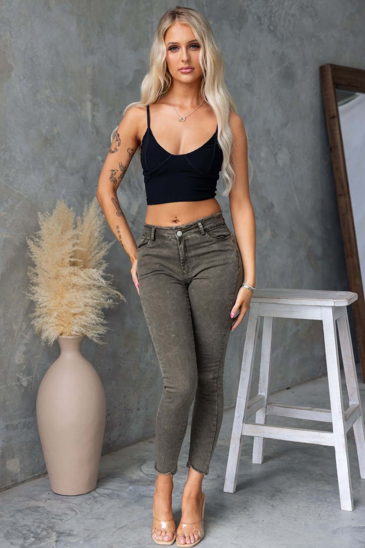 Model wearing Cassander Jeans with frayed waistband and cuffs, paired with a black top and stylish sandals.