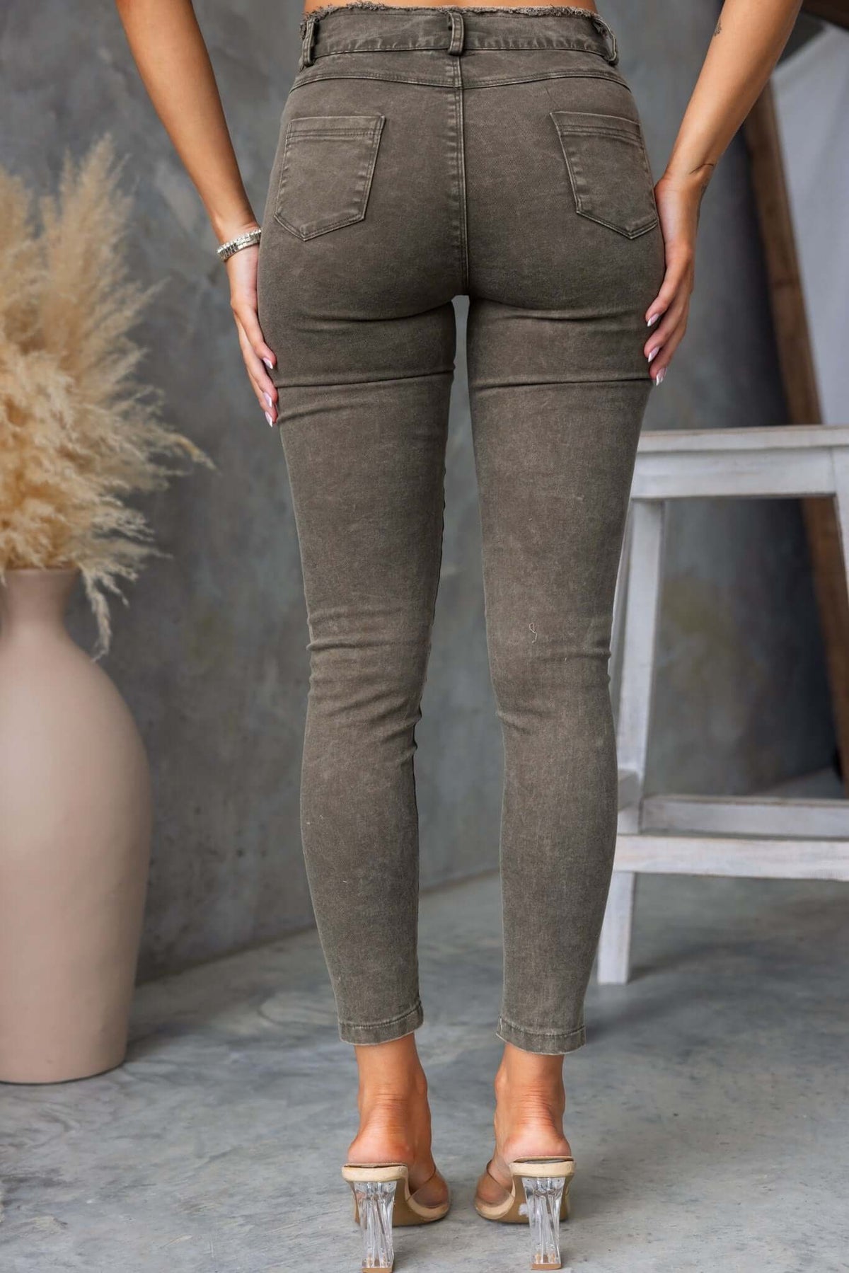 Back view of Cassander jeans featuring skinny fit and frayed cuffs, styled with clear heels and minimal accessories.