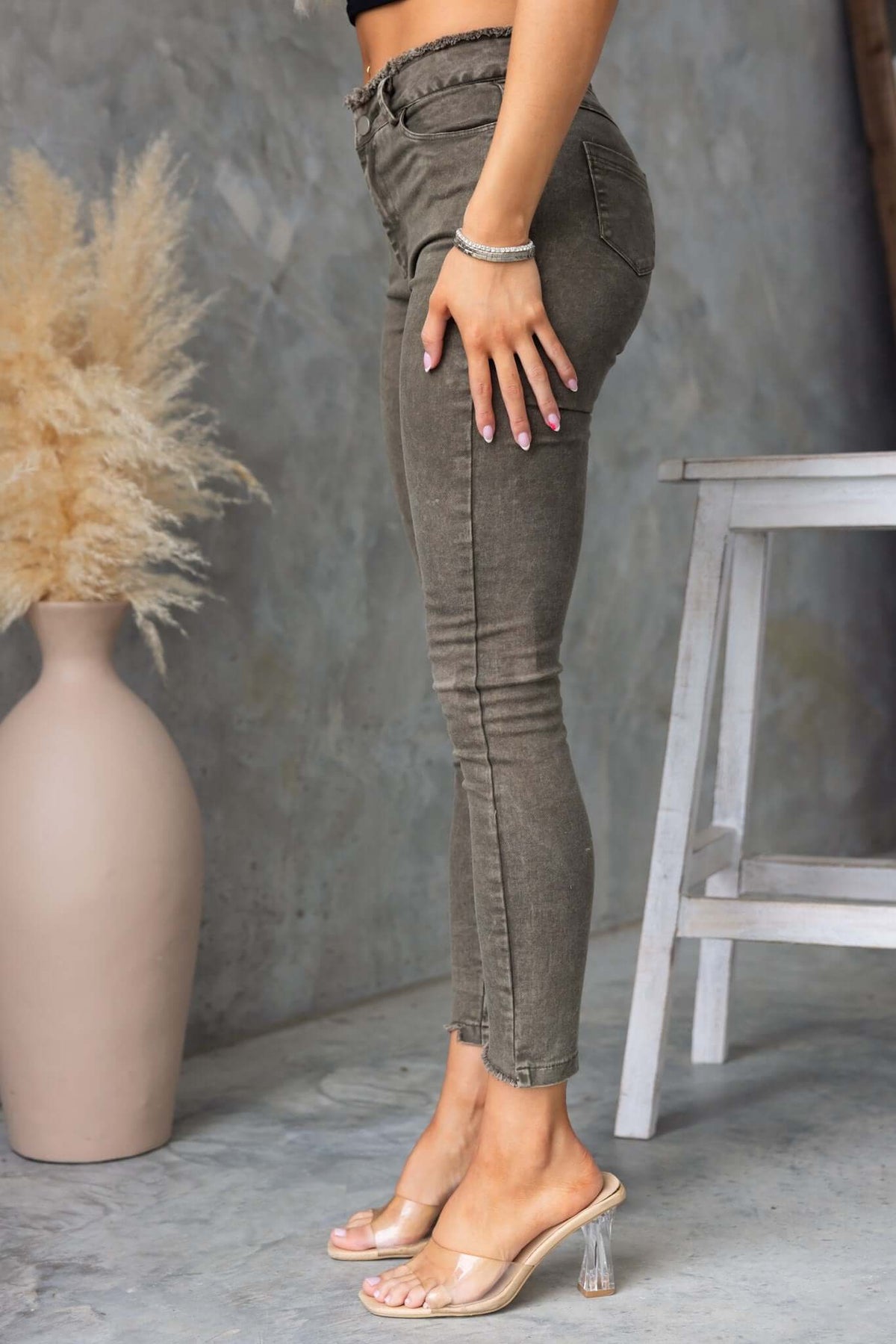 Model showcasing Cassander Jeans with frayed waistband and cuffs in a stylish fit against a textured backdrop.
