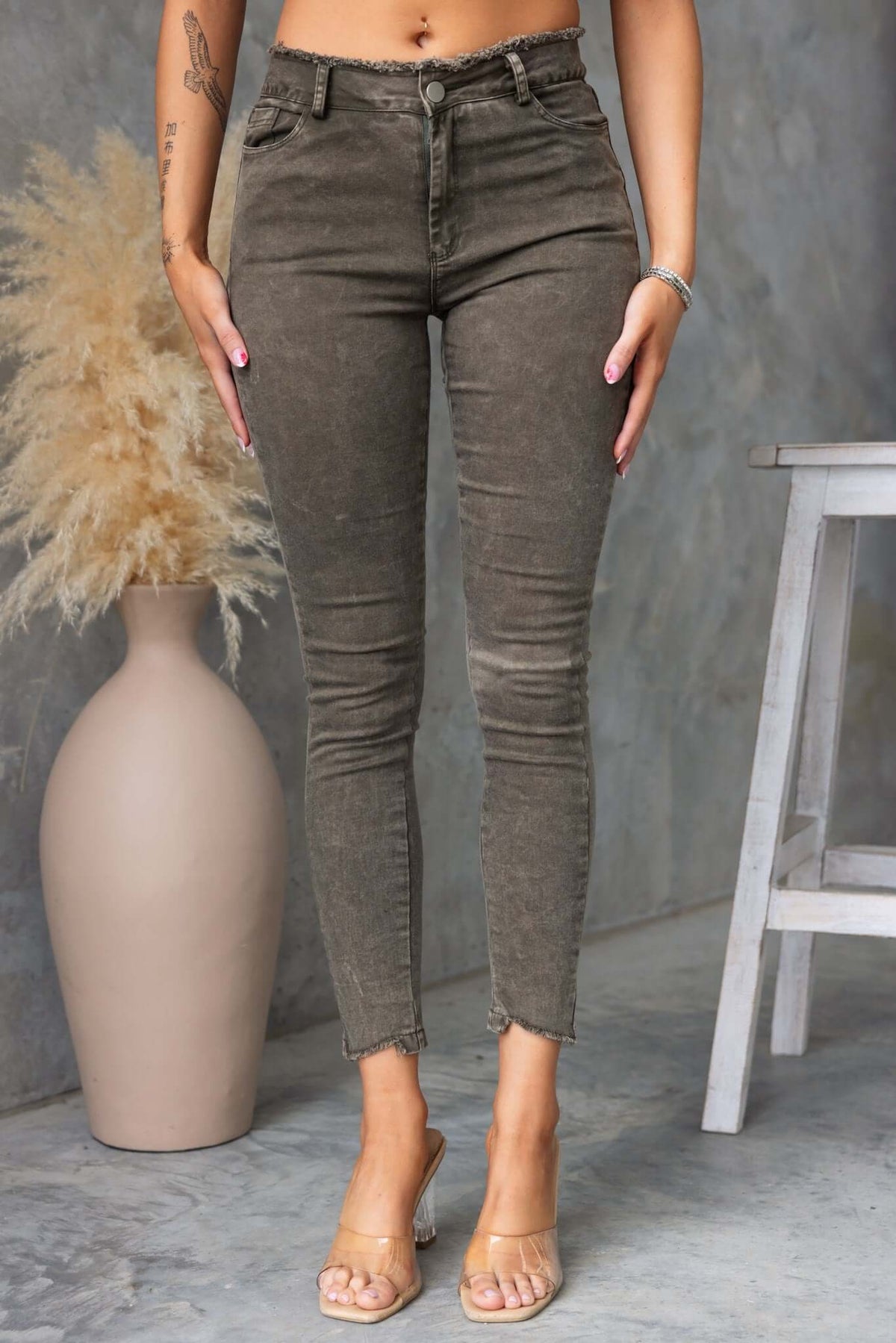 Women wearing Cassander jeans featuring a frayed waistband and cuffs in a stylish olive green color.