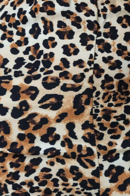 Close-up of leopard print fabric featuring brown and black spots on a cream background for stylish shorts.