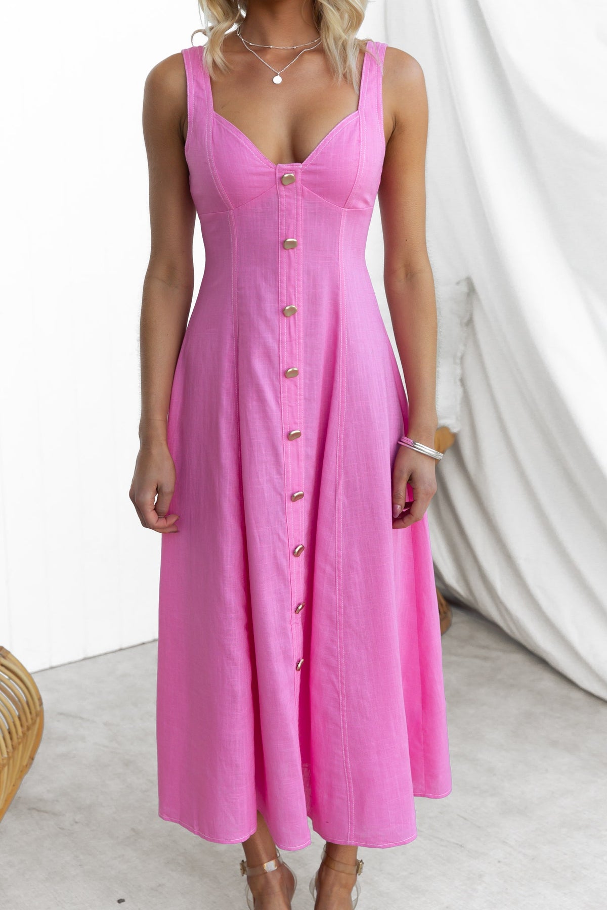 Model wearing a pink Lyre Midi Dress with faux buttons and a fitted bodice, perfect for summer occasions.