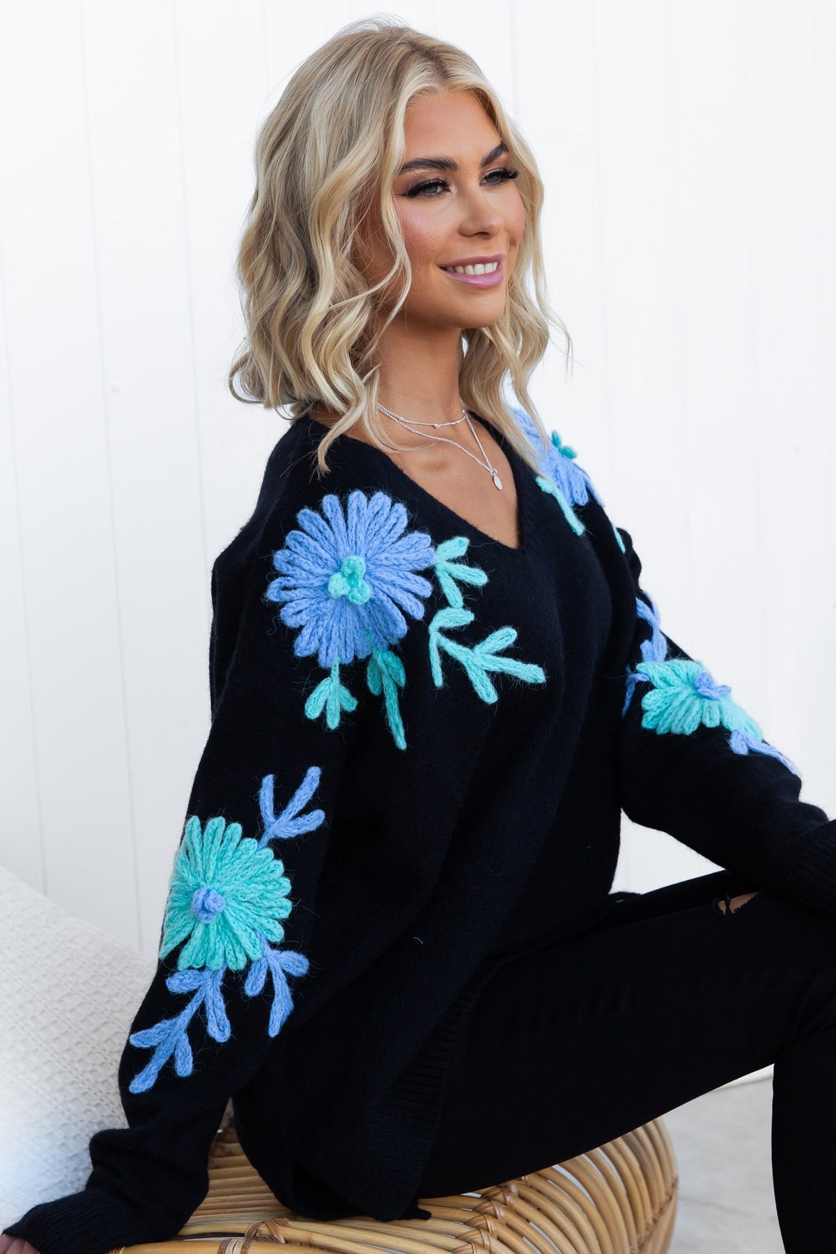 Stylish black jumper with V-neckline and floral embroidery, featuring a relaxed fit and side splits.