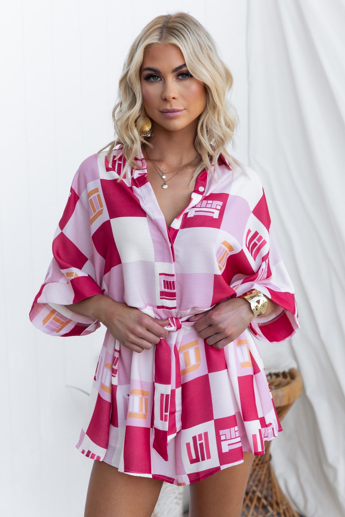 Model wearing a pink and white abstract print Sundown Playsuit with collar and removable fabric tie.