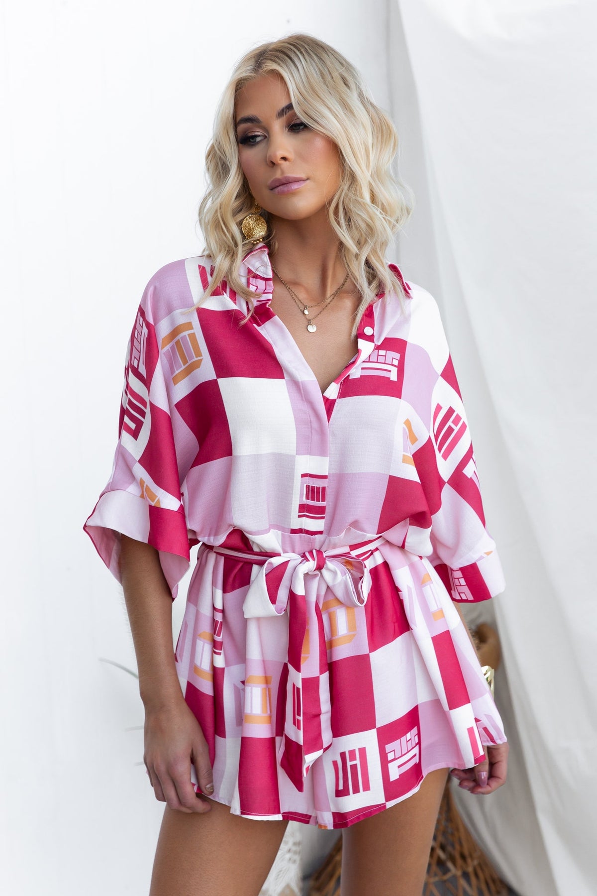 Model wearing a pink and white abstract print Sundown playsuit with a collar and removable tie.