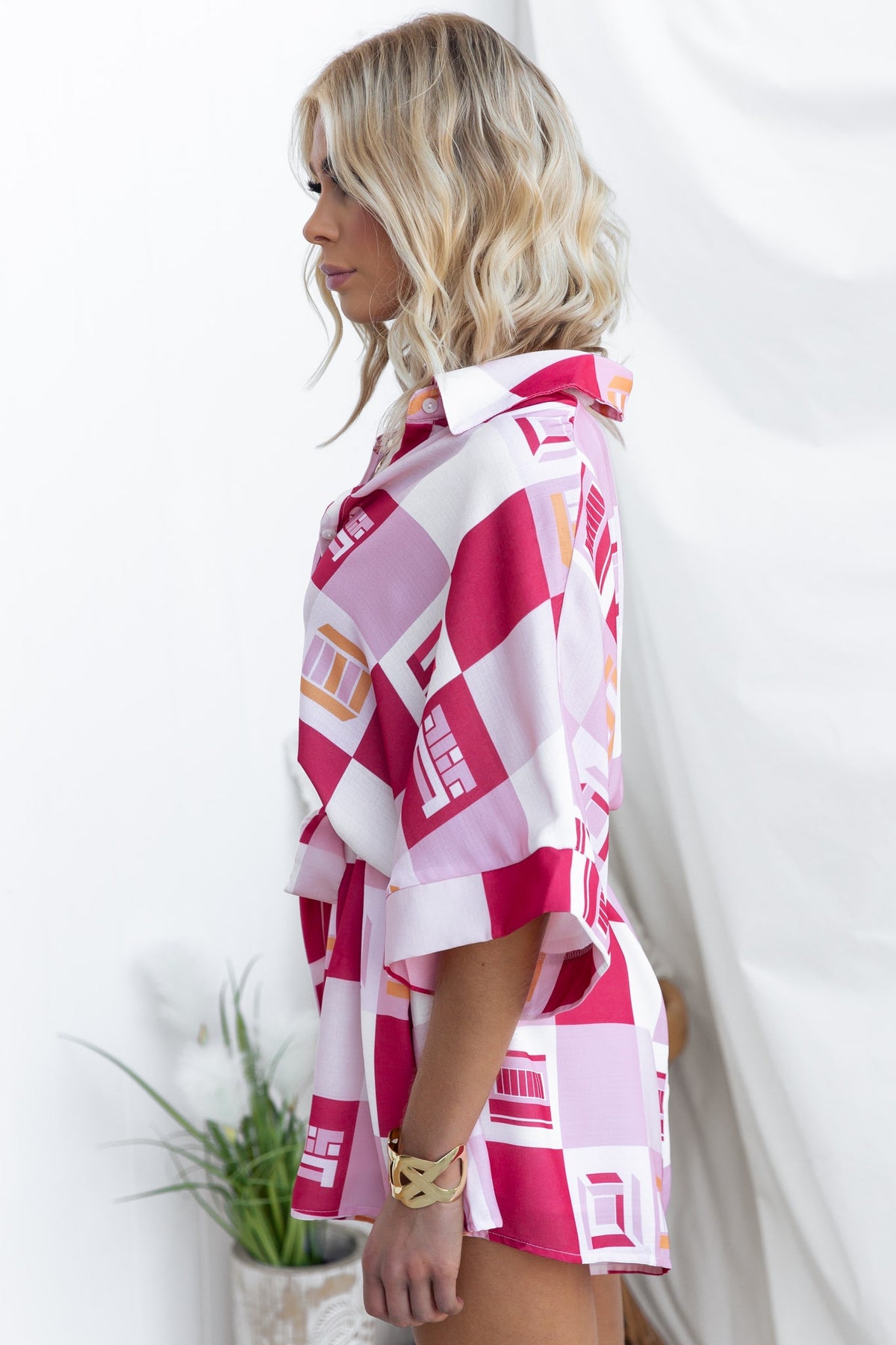 Sundown Playsuit in abstract pink print, featuring a collar and button-up design, styled with a removable tie.