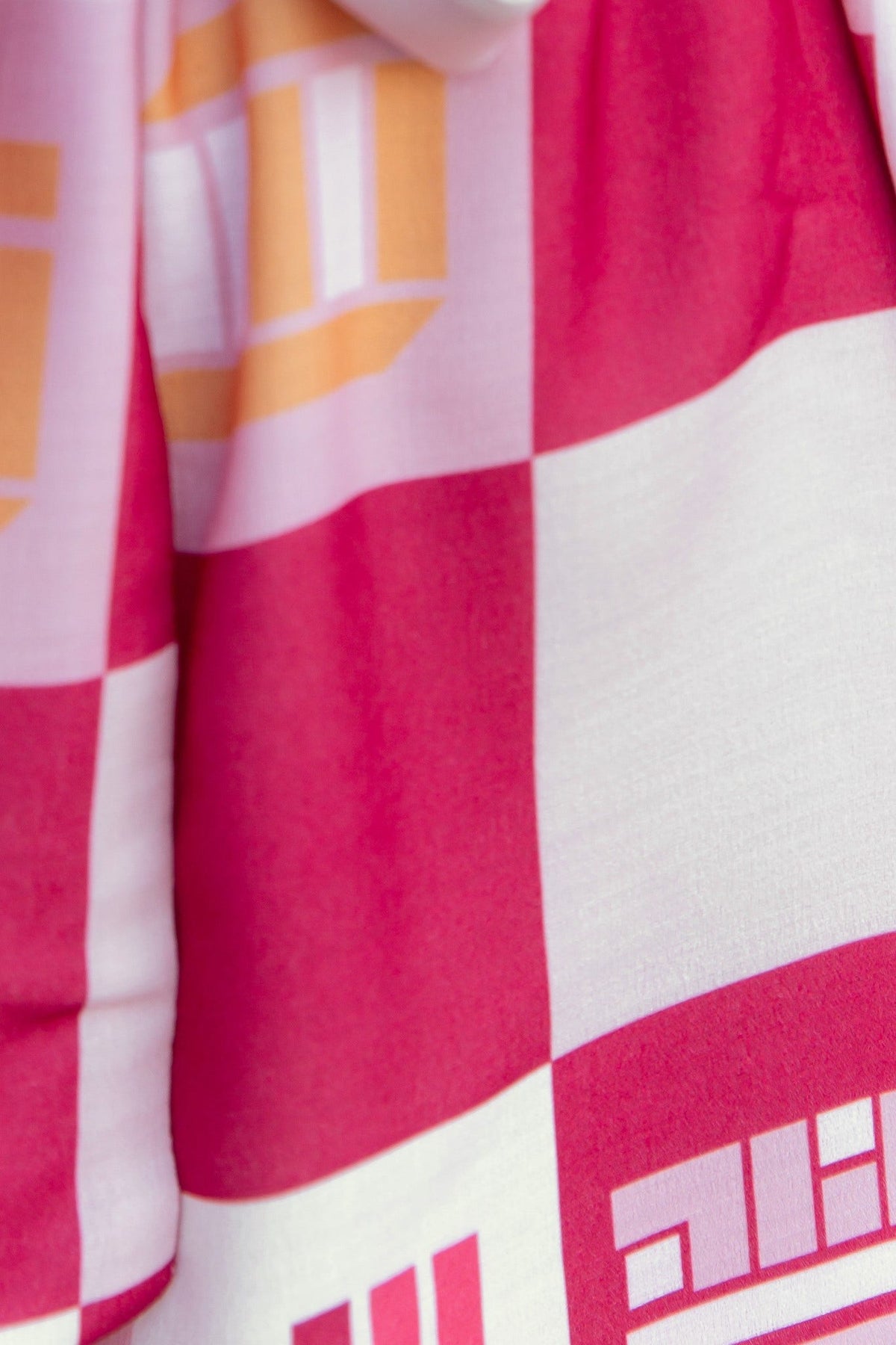 Close-up of Sundown Playsuit showcasing vibrant abstract print in pink and orange checkered pattern.