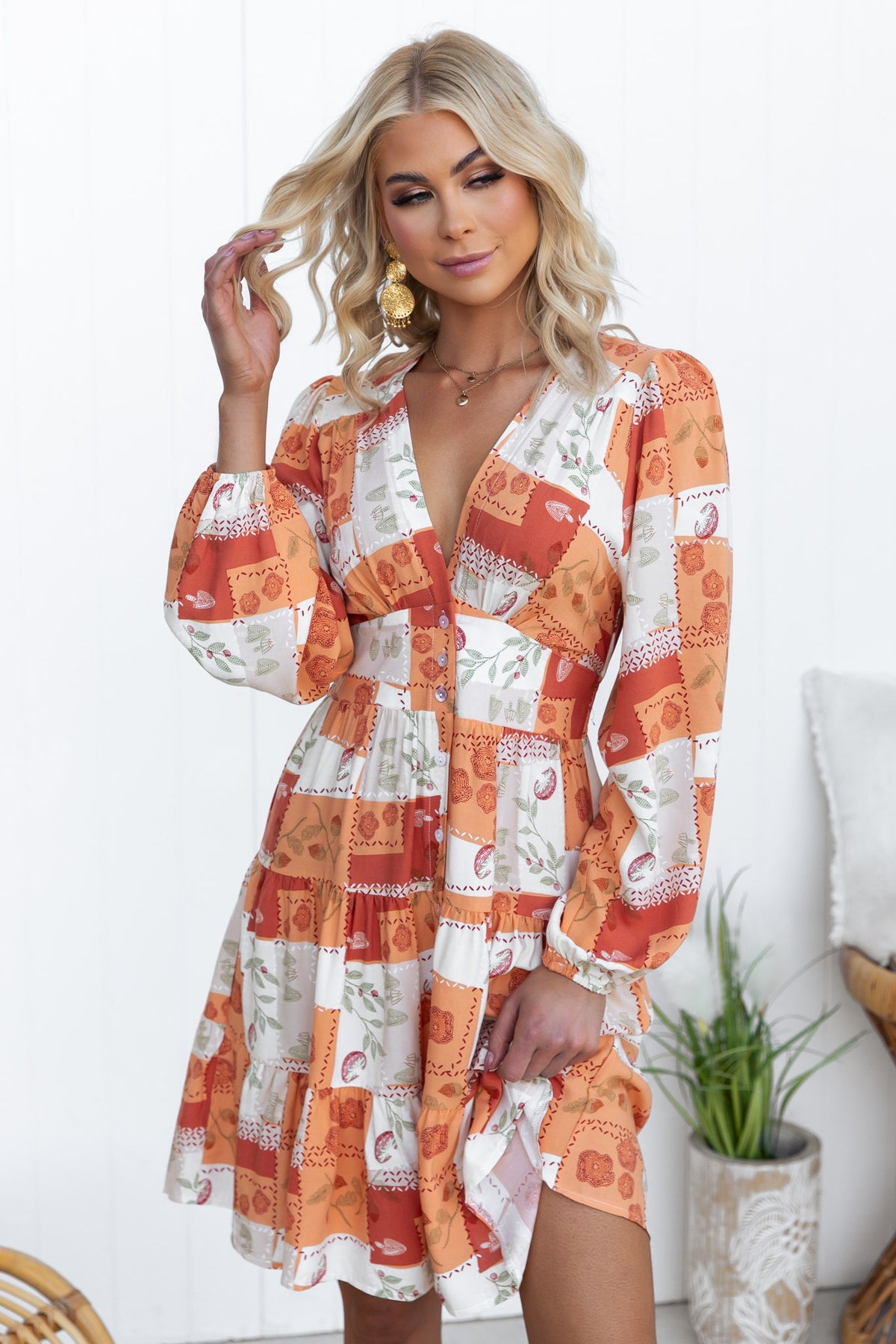 Coral dress with V-neckline and button-up front, featuring long sleeves and a stylish patchwork design.