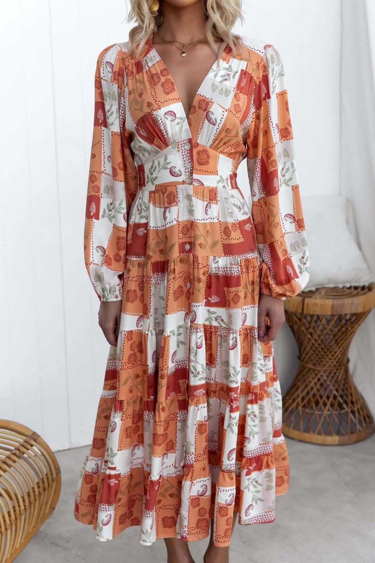 Coral midi dress with V-neckline and button-up front, featuring elastic cuffs and waistband, styled for a casual look.