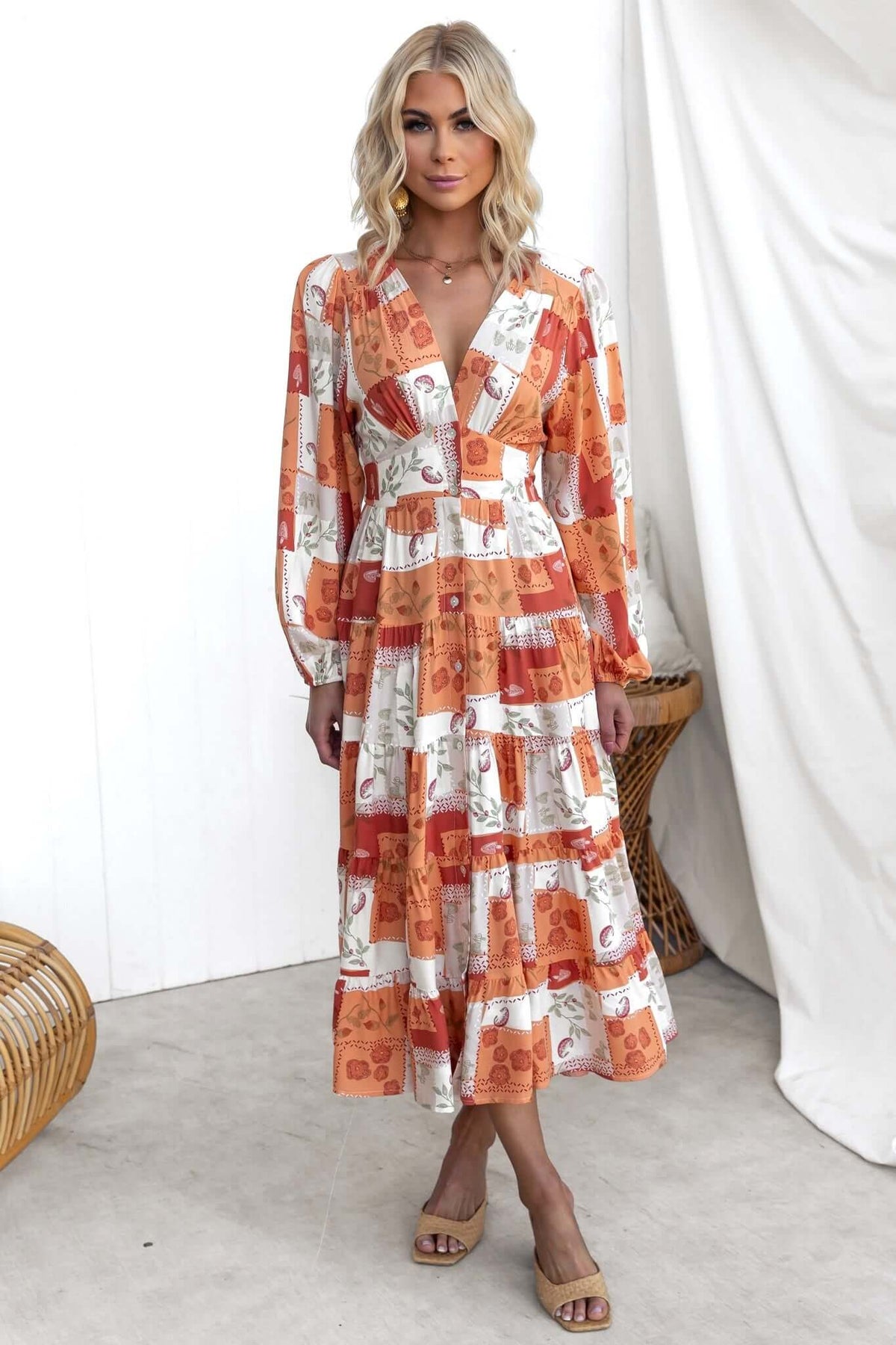 Coral midi dress with V-neckline and button-up front, featuring a floral pattern and elastic cuffs, worn by a model.