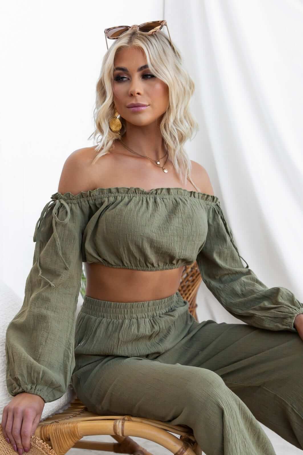 Woman wearing a stylish off-shoulder Gravina Top in olive green, paired with matching pants, showcasing a trendy summer look.