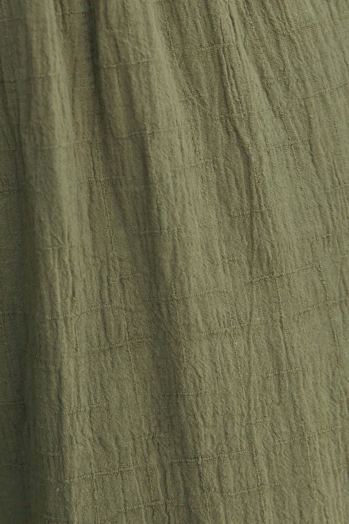 Close-up of soft green fabric texture, showcasing a lightweight cotton feel, ideal for casual wear like tops and dresses.