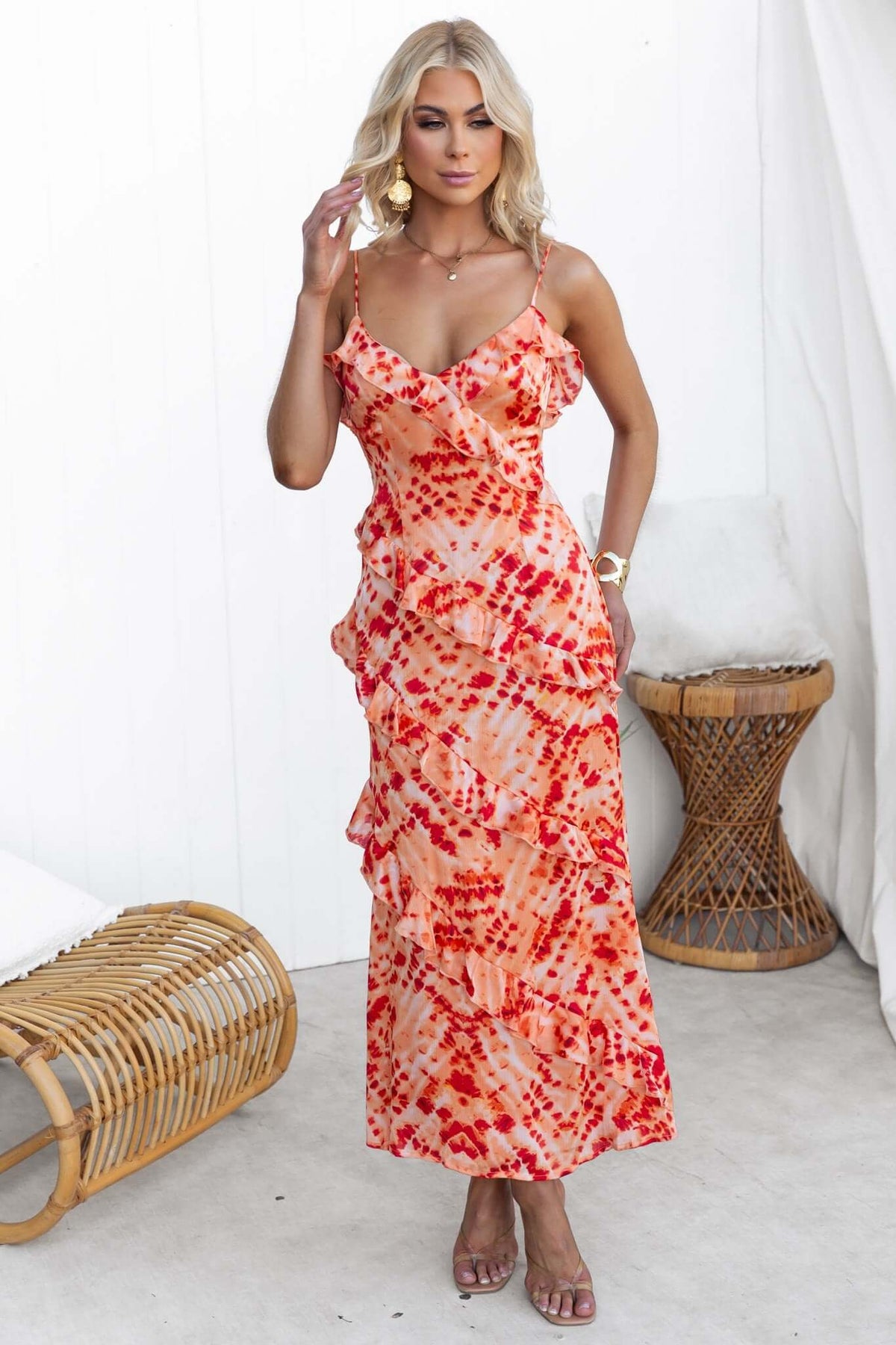 Model wearing an Aquarius Print Maxi Dress with adjustable straps and ruffle detailing in vibrant red and orange hues.
