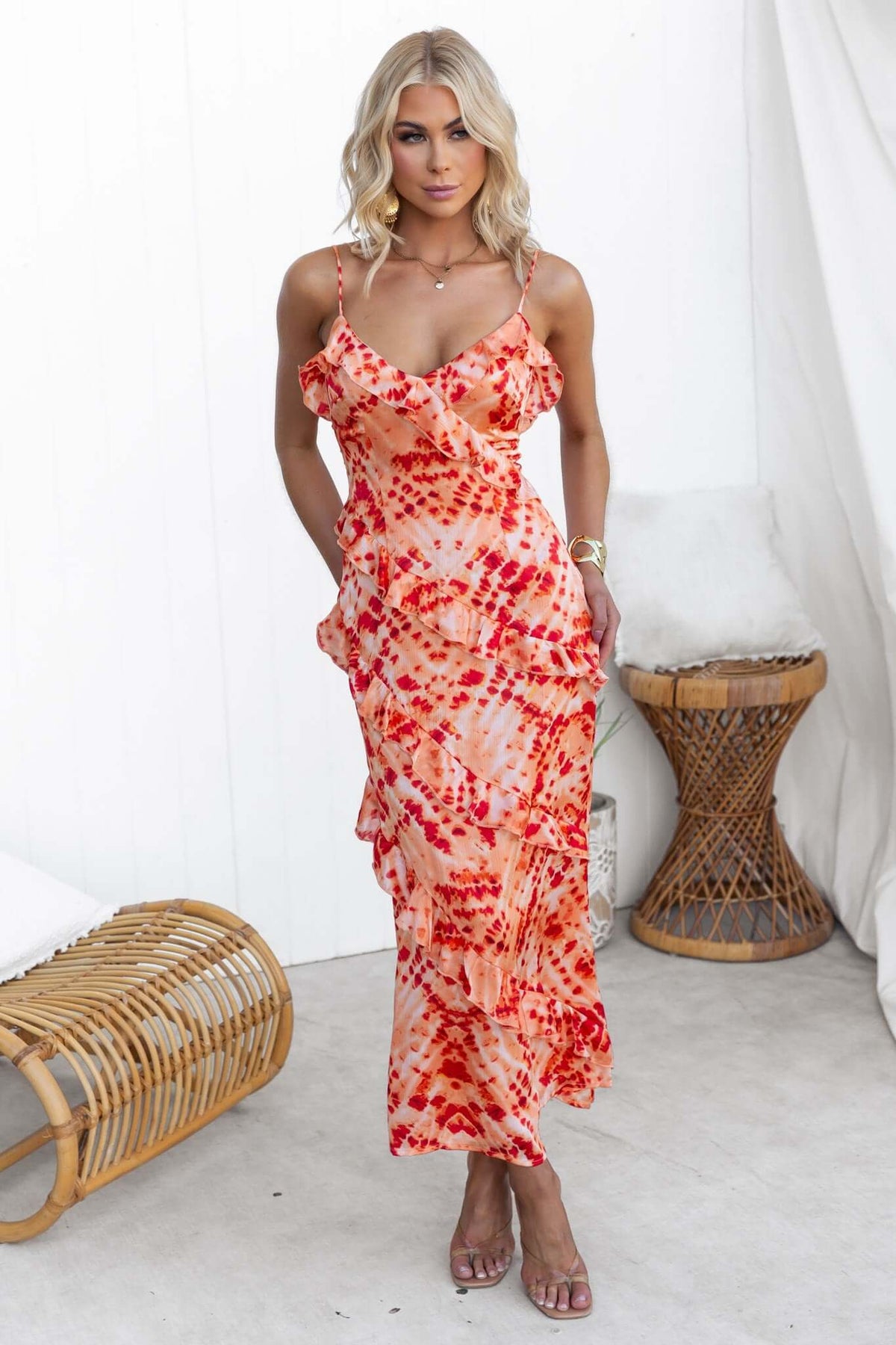 Model wearing an orange and red print Aquarius maxi dress with adjustable straps and ruffle detailing.