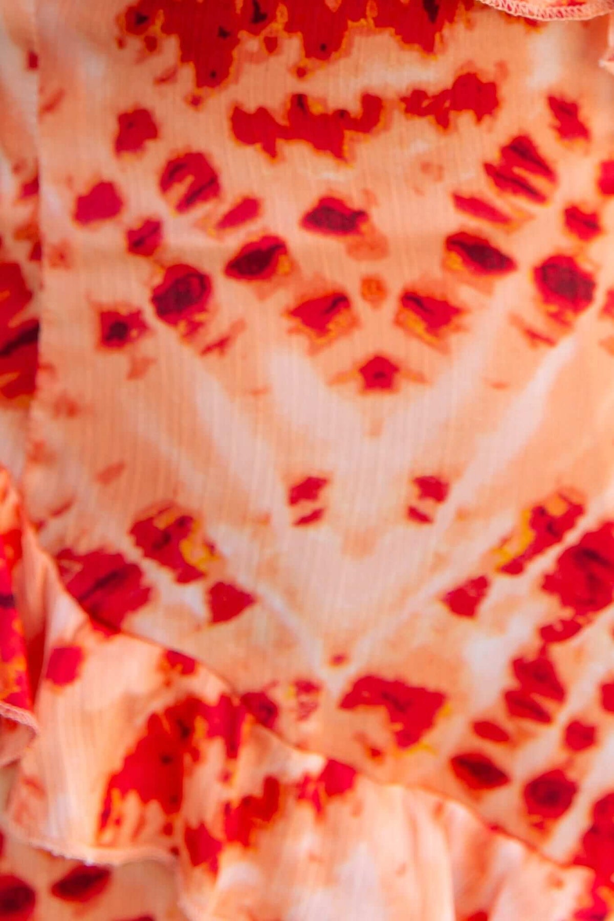 Close-up of vibrant orange and red print on a maxi dress with ruffle detailing