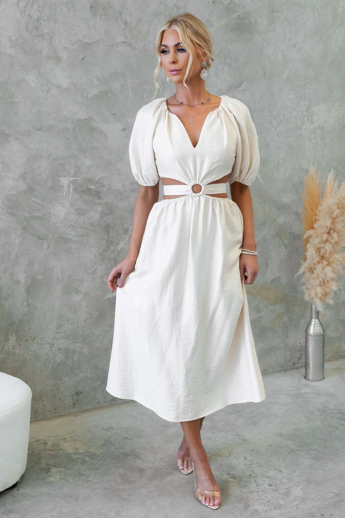 Isabelline midi dress featuring a V-neckline, puffed sleeves, and a cut-out waist detail in a stylish setting.