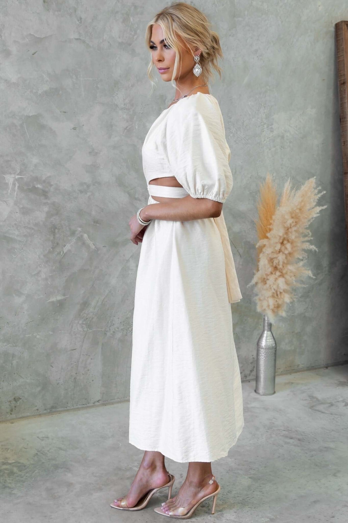 Isabelline midi dress featuring a V-neckline, cut-out waist, and attached fabric tie, styled elegantly.