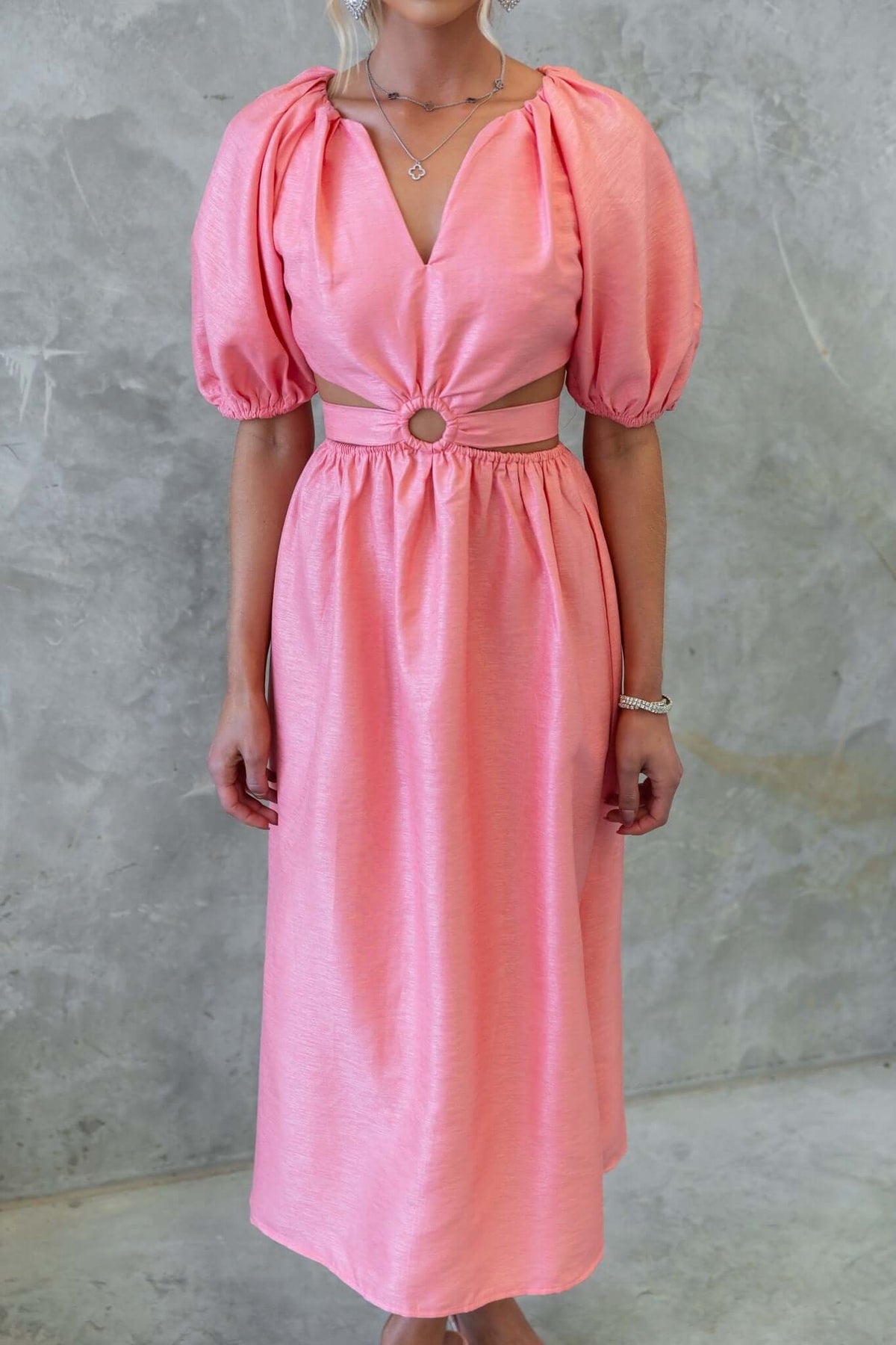 Isabelline midi dress in vibrant pink with puff sleeves and cut-out waist detail, perfect for stylish summer events.