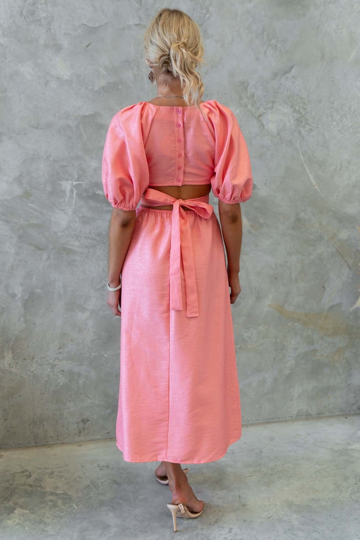 Back view of a pink Isabelline midi dress featuring puff sleeves and an elastic waistband with a fabric tie.