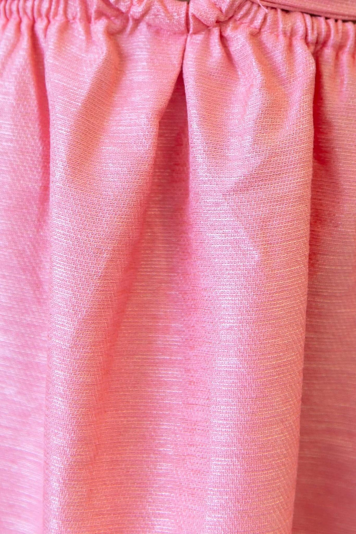 Close-up of the gathered elastic waistband detail on a pink midi dress fabric.
