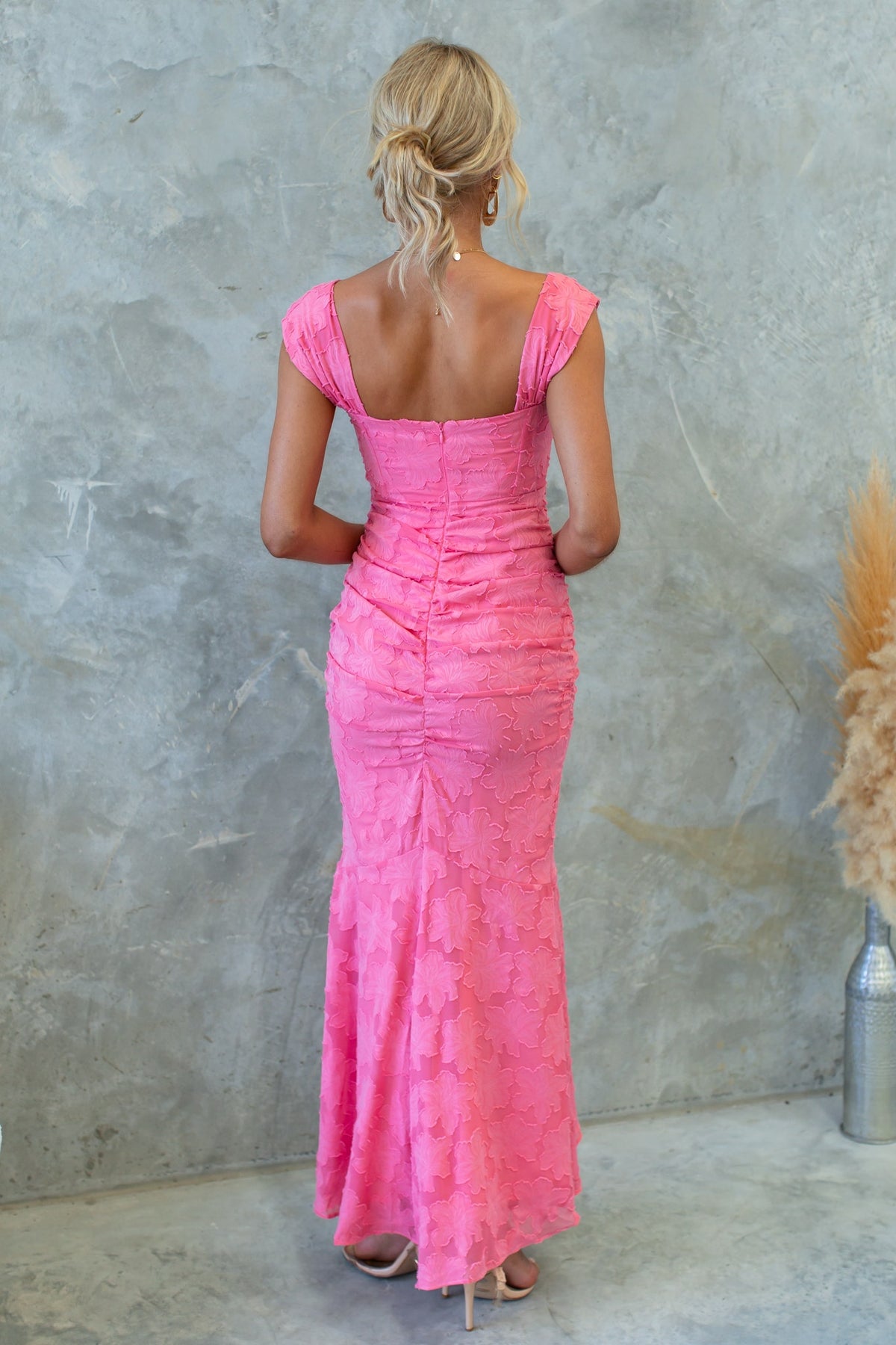 Back view of a pink Arezzo Maxi Dress featuring ruching, cap sleeves, and a flared bottom.