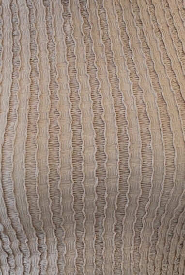 Textured beige fabric featuring vertical stripes, showcasing a stylish and modern design perfect for fashion apparel.