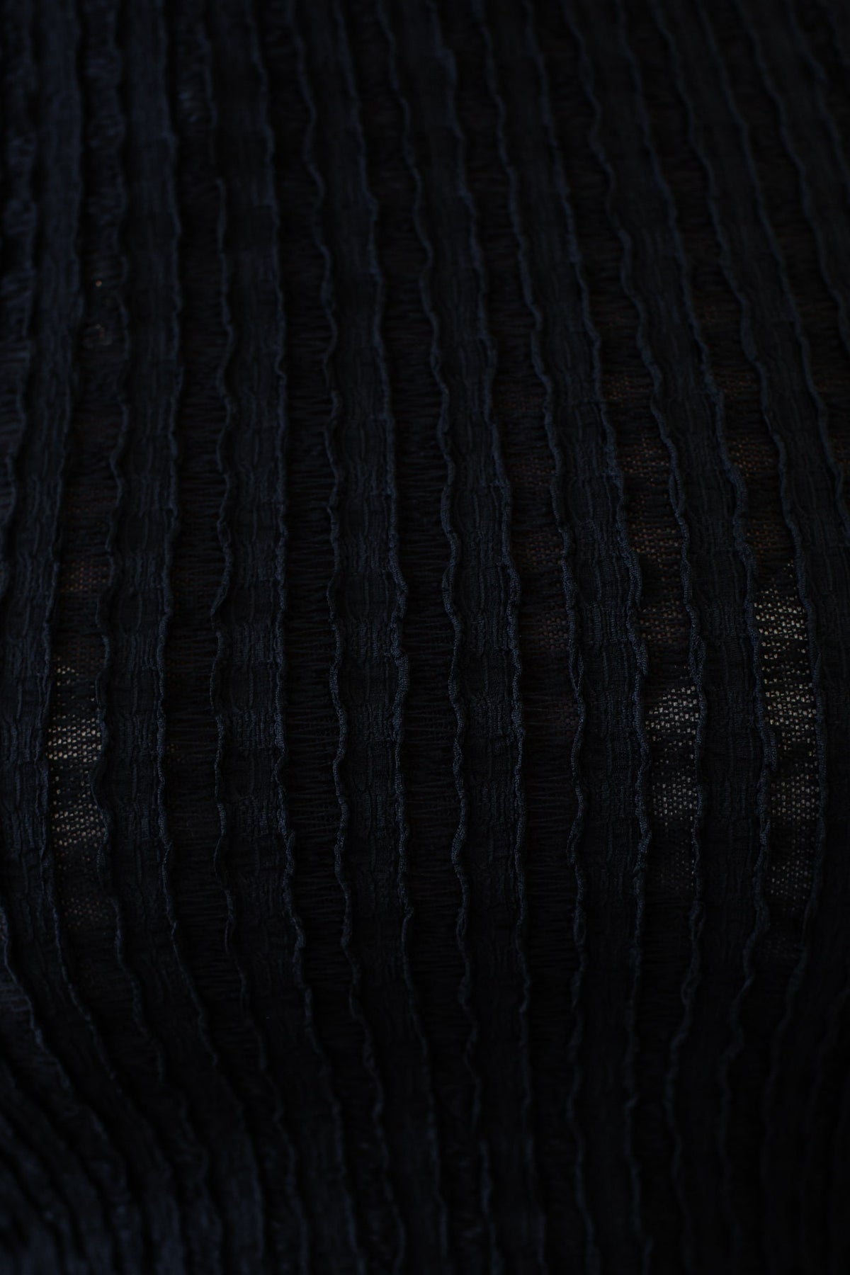 Close-up of black textured fabric showcasing vertical stripes, ideal for stylish tops like the Over It Top.